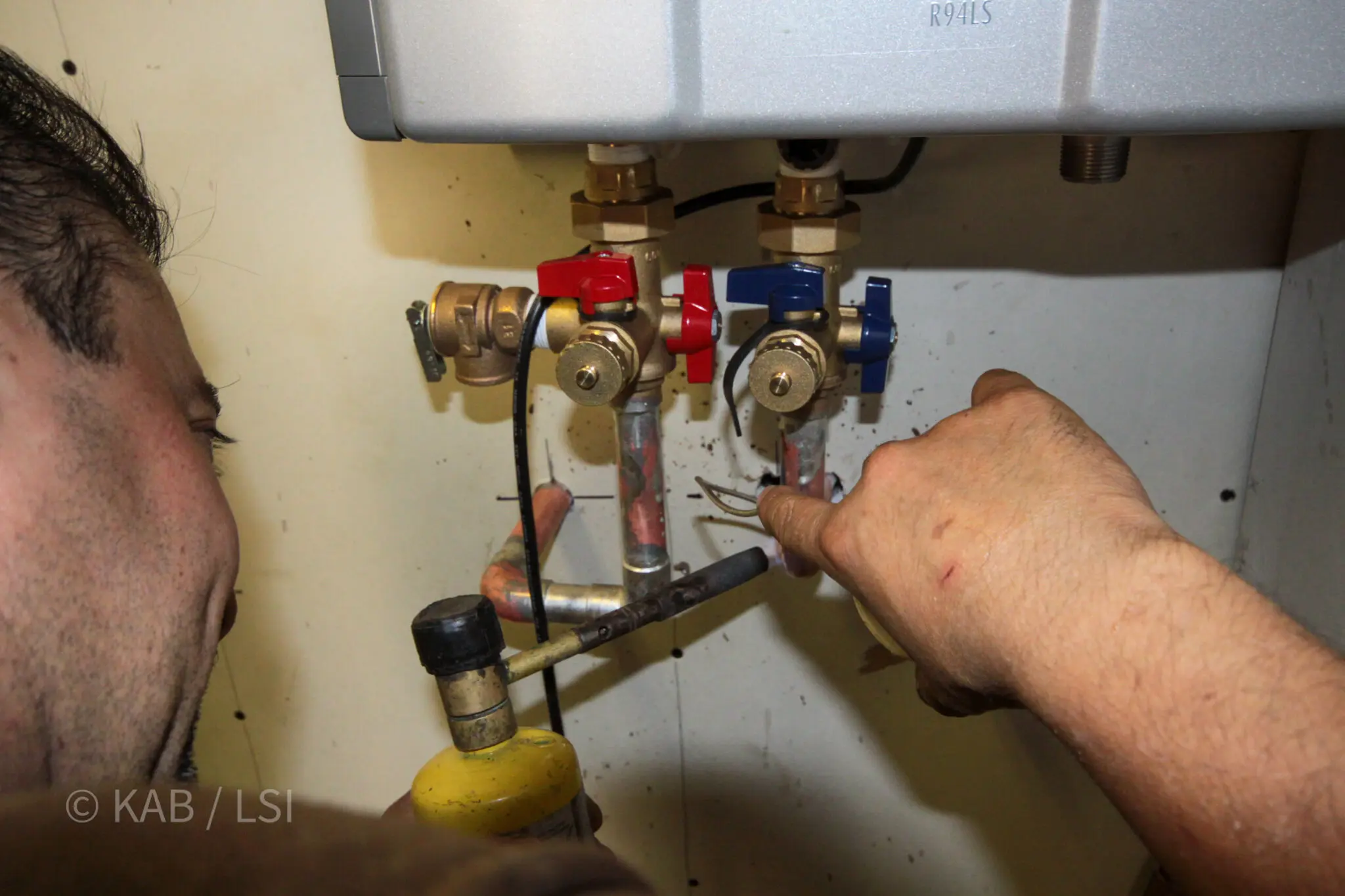 Handyman installing and servicing a residential tankless water heater during a skills evaluation