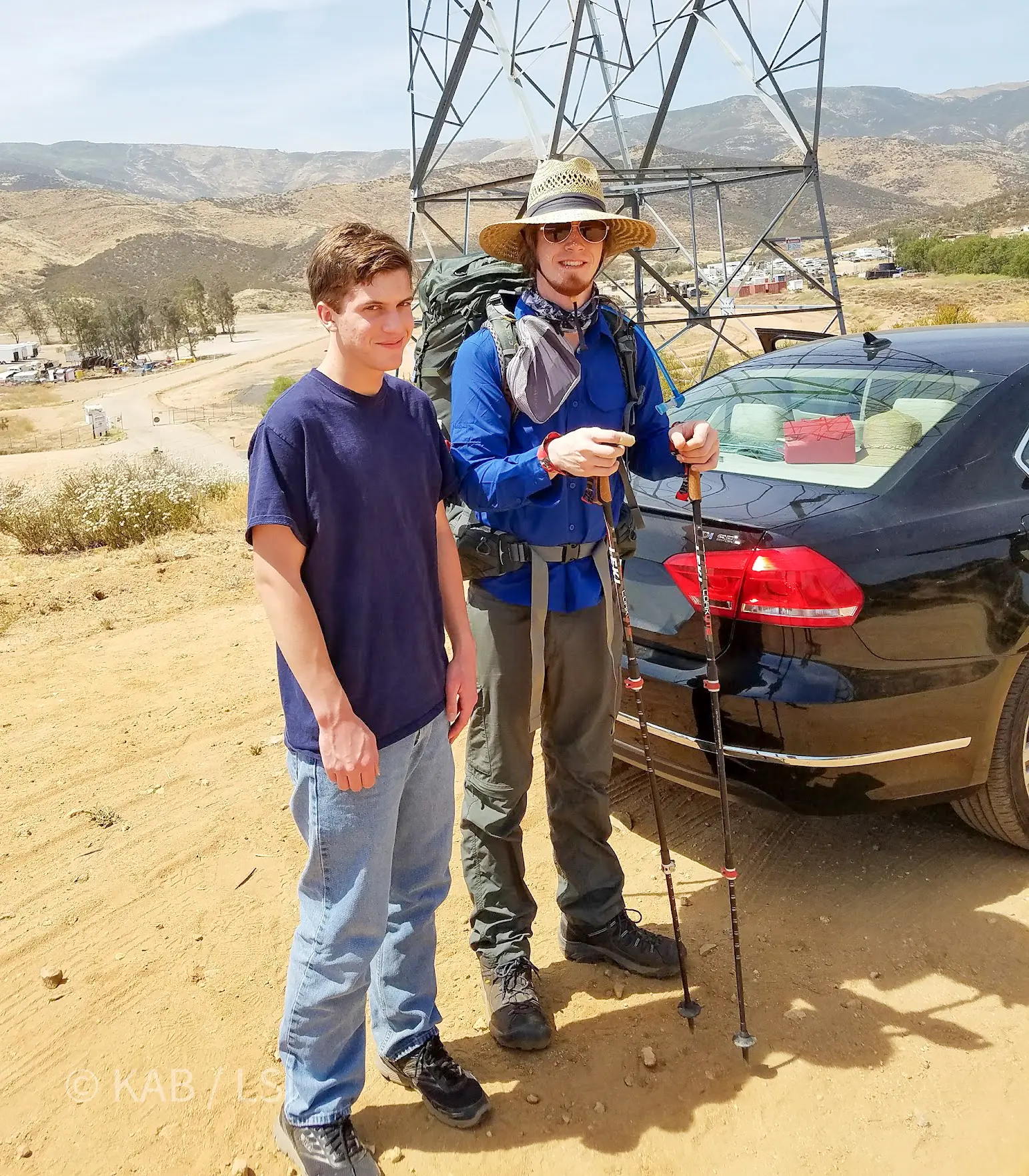 Joshua Bennett at 24 and his younger brother Alex Bennett at 18 at the southern terminus of the Pacific Crest Trail near Campo, California on June 1, 2016. Joshua wears a wide brimmed sun hat and a full pack with trekking poles. Alex wears jeans and a t-shirt and is about to drive home.
