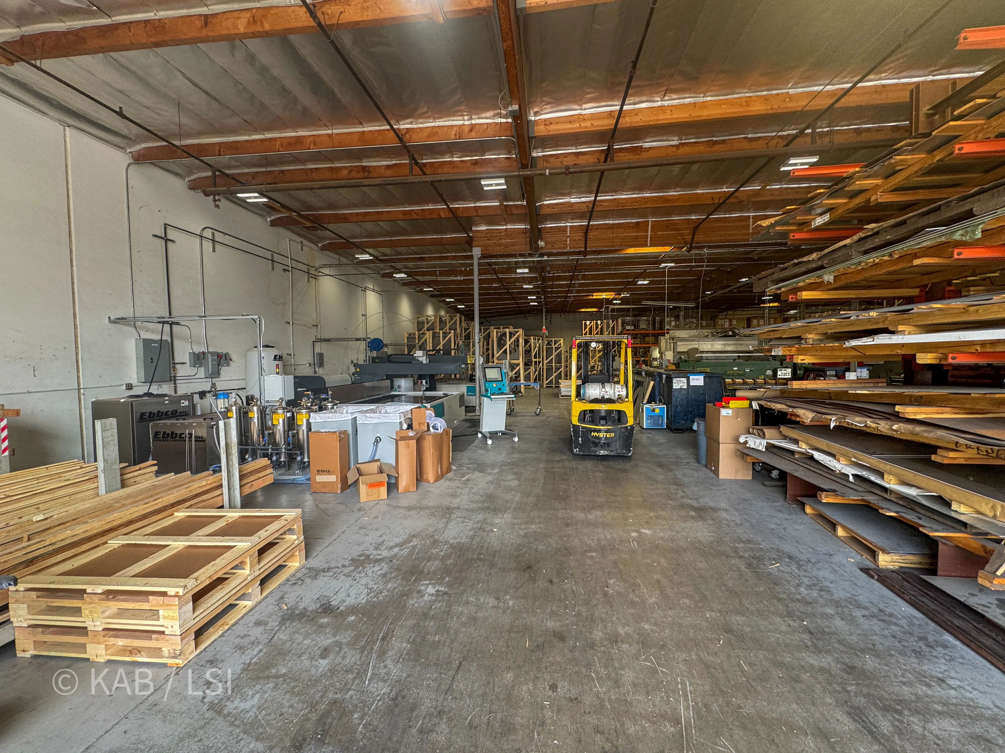 Interior view of the ToroAire fabrication floor showing a water-jet CNC cutting table, Ebbco closed-loop water filtration units, sheet stock racking, and a Hyster propane forklift.