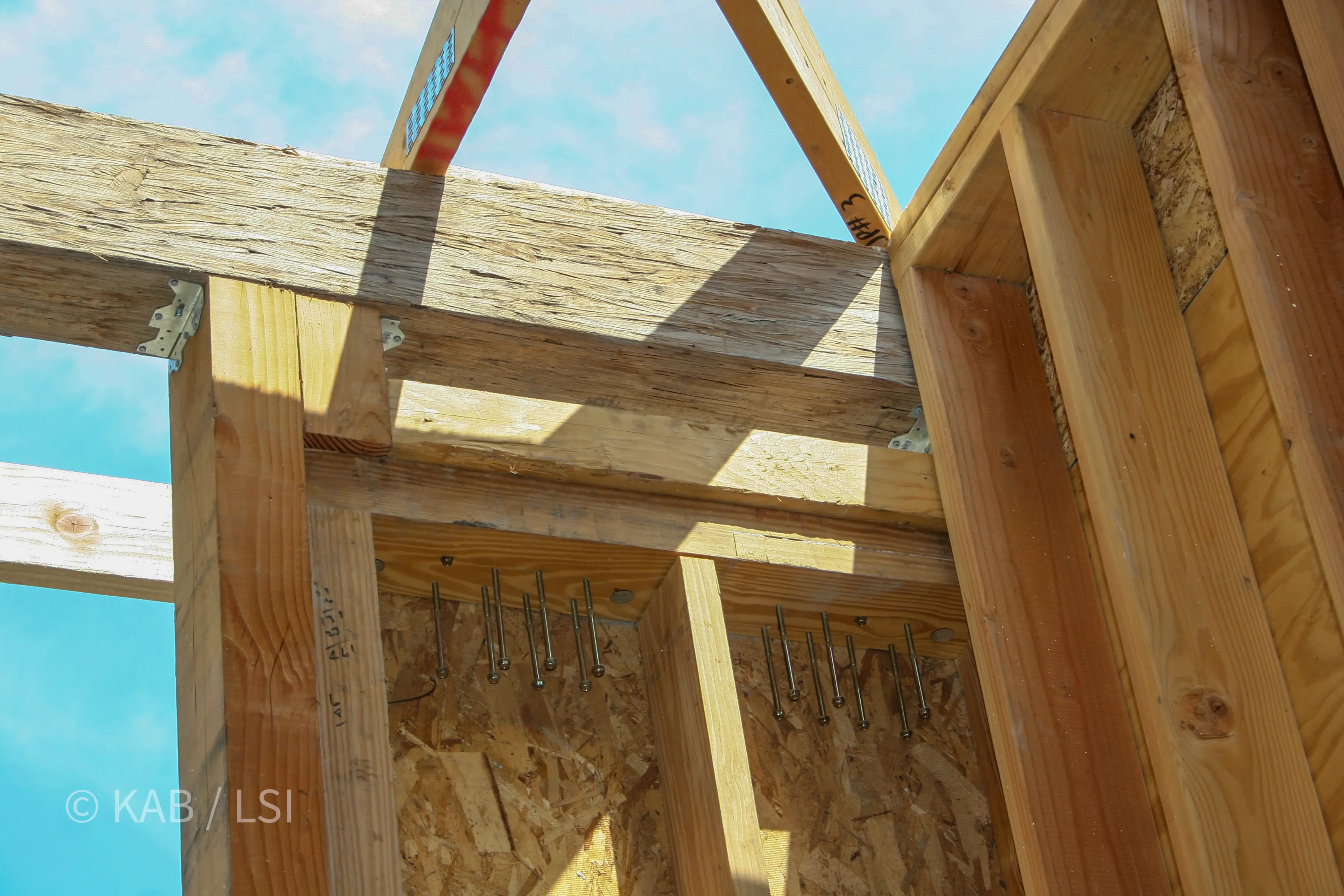 Hold-down bolts protruding from sheathing at the ridge — seismic tie-down detail © KAB/LSI