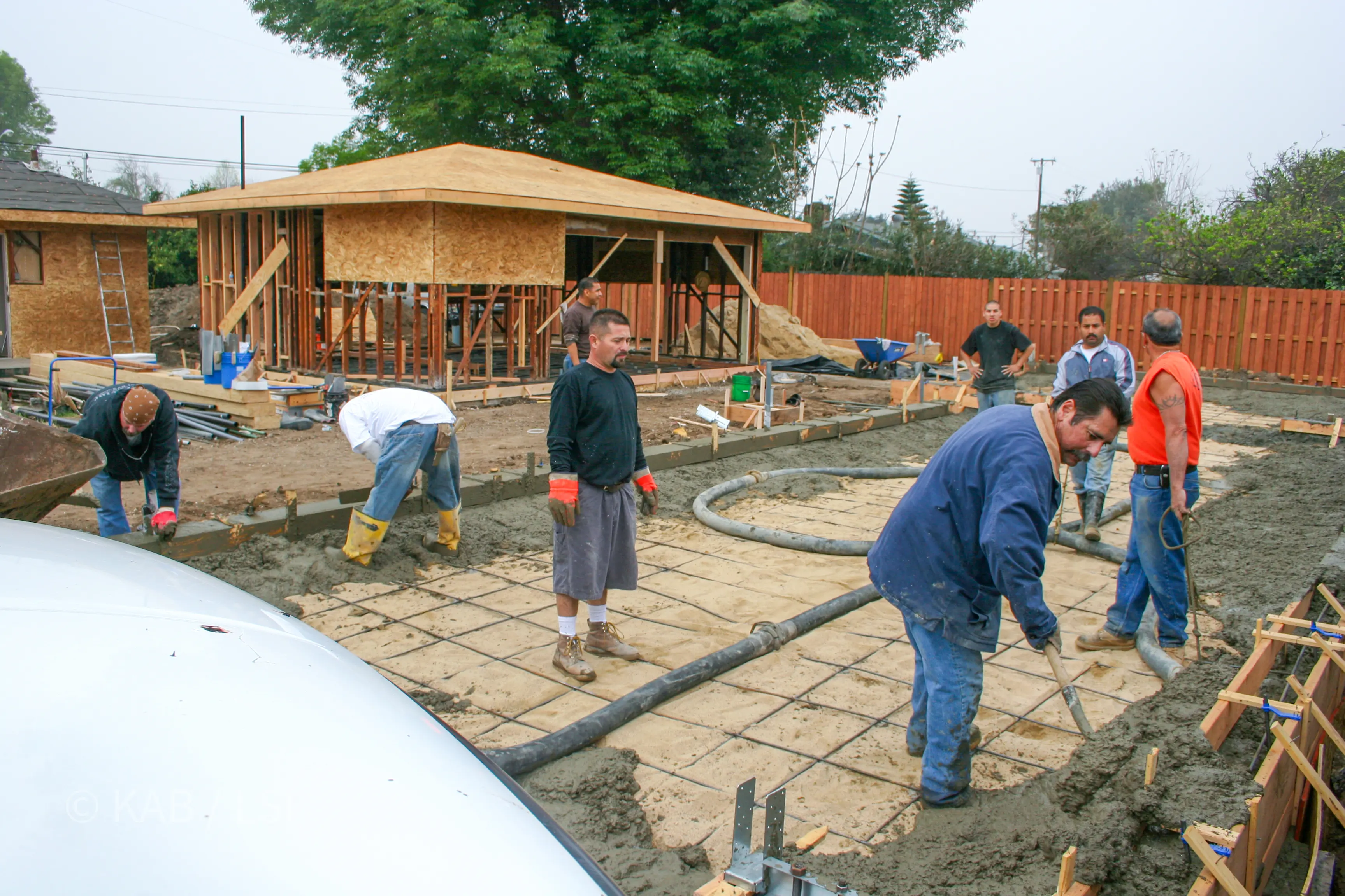 Eight-man crew pouring the RV garage perimeter footing — panoramic view of the monolithic pour © KAB/LSI