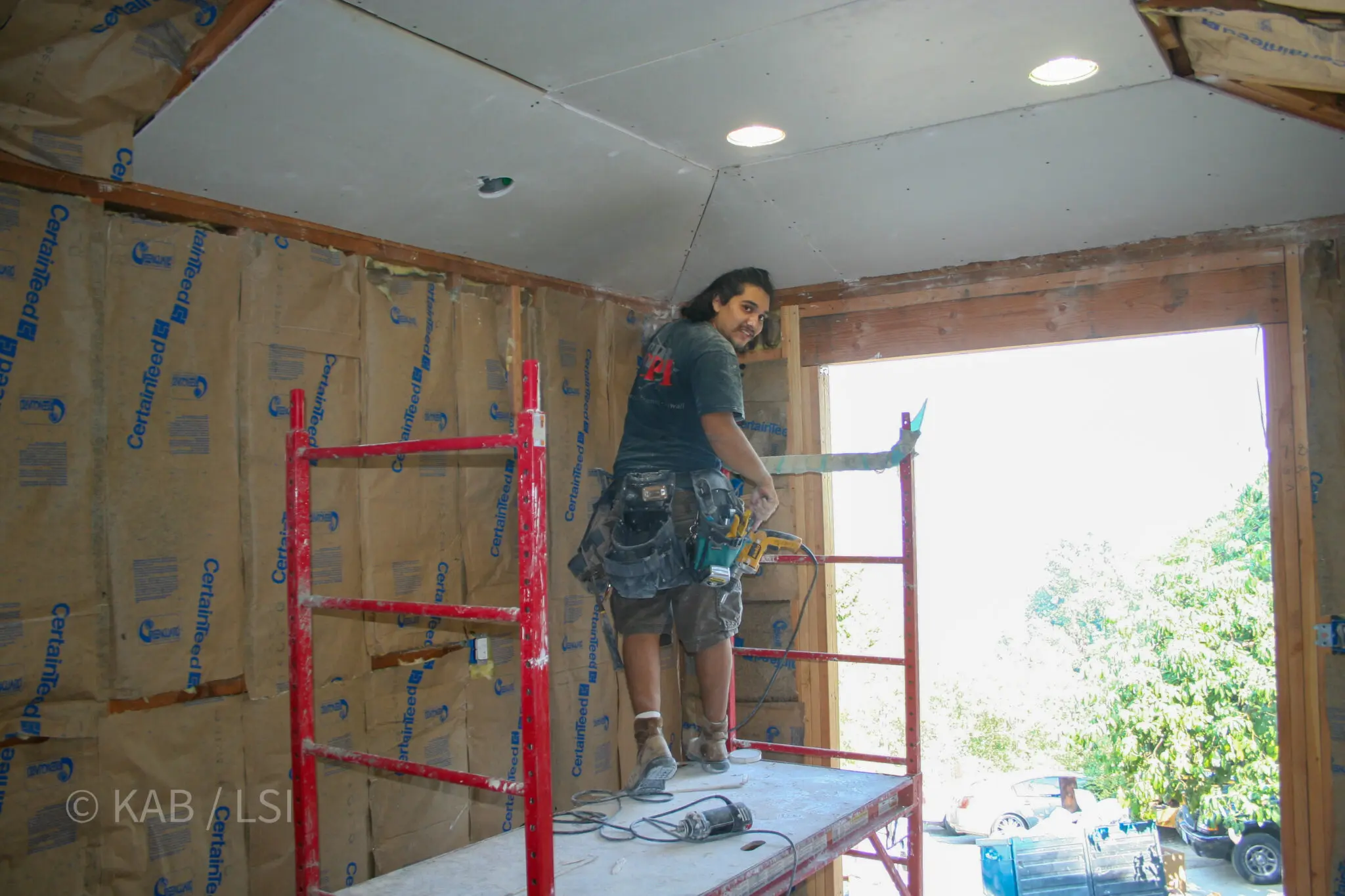 A pastor on scaffolding installing drywall on a cathedral ceiling in a newly reframed La Habra Heights master bedroom