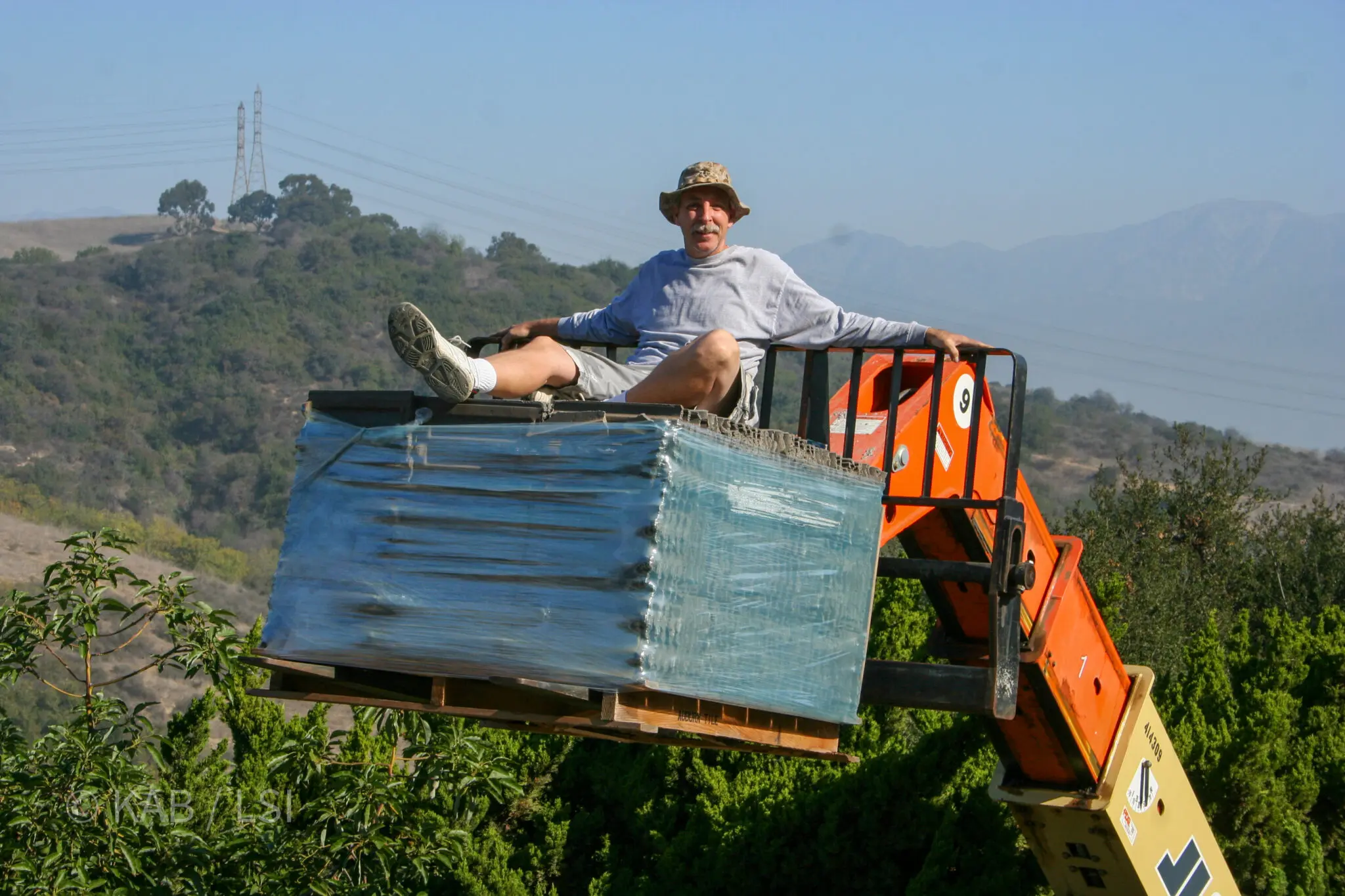 Foreman Kyle riding the first 2,000-pound pallet of Auburn fire-resistant concrete roof tiles up to a newly prepared La Habra Heights hillside roof on a telehandler