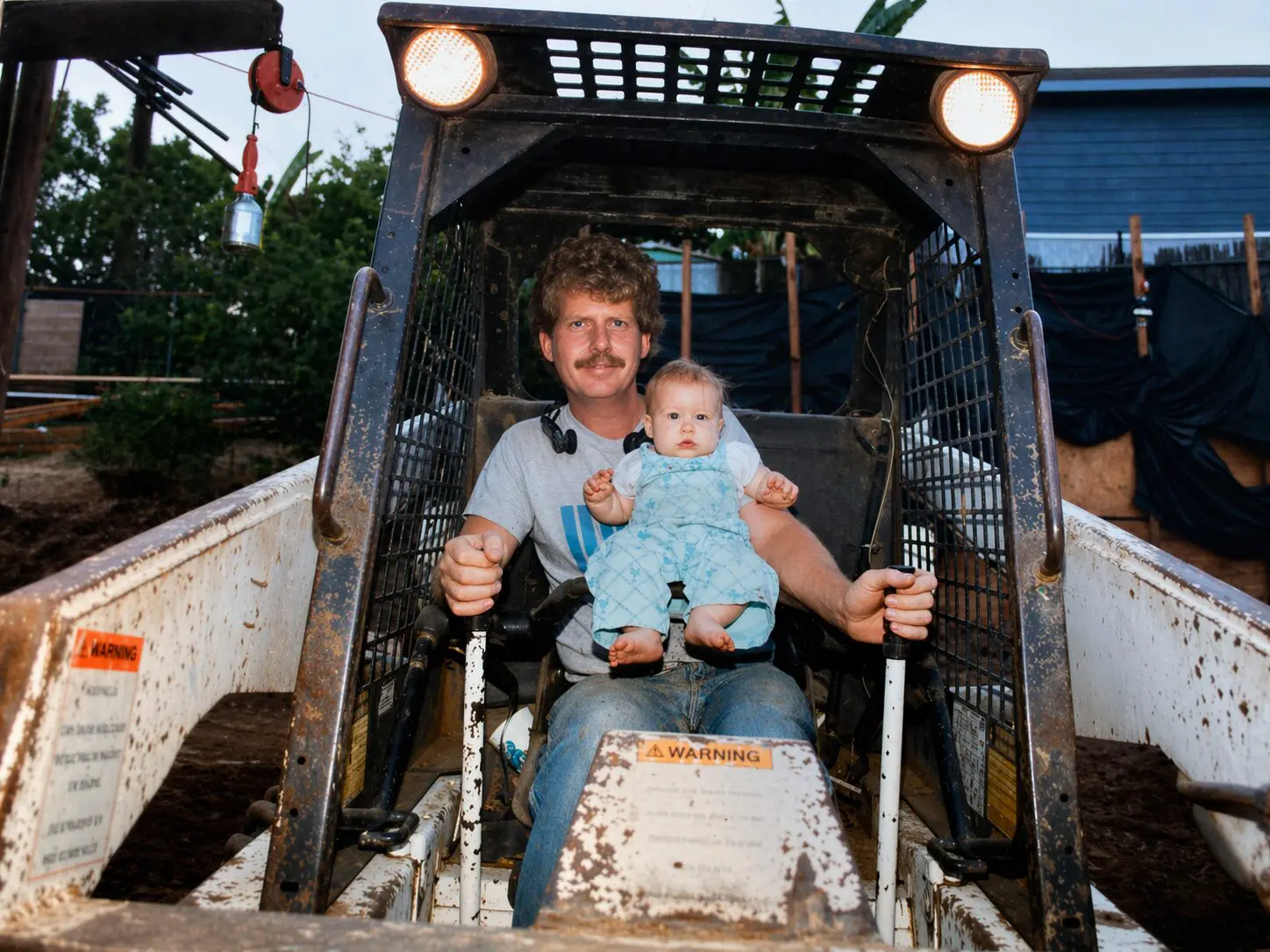 Keith Bennett in 1988 seated in a skid steer holding his infant daughter Megan on his lap on a La Mirada construction site.