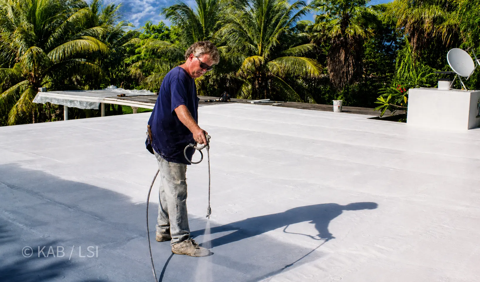 Keith Bennett at 46, photographed on a Miami Beach roof in July 1999, spraying elastomeric cool-roof coating.