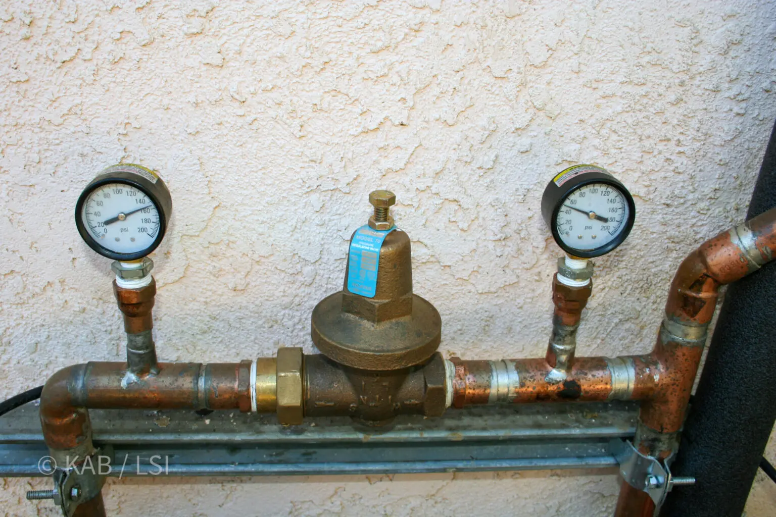 Watts brand pressure reducing valve installed on copper supply line with pressure gauges on both the city side and the house side