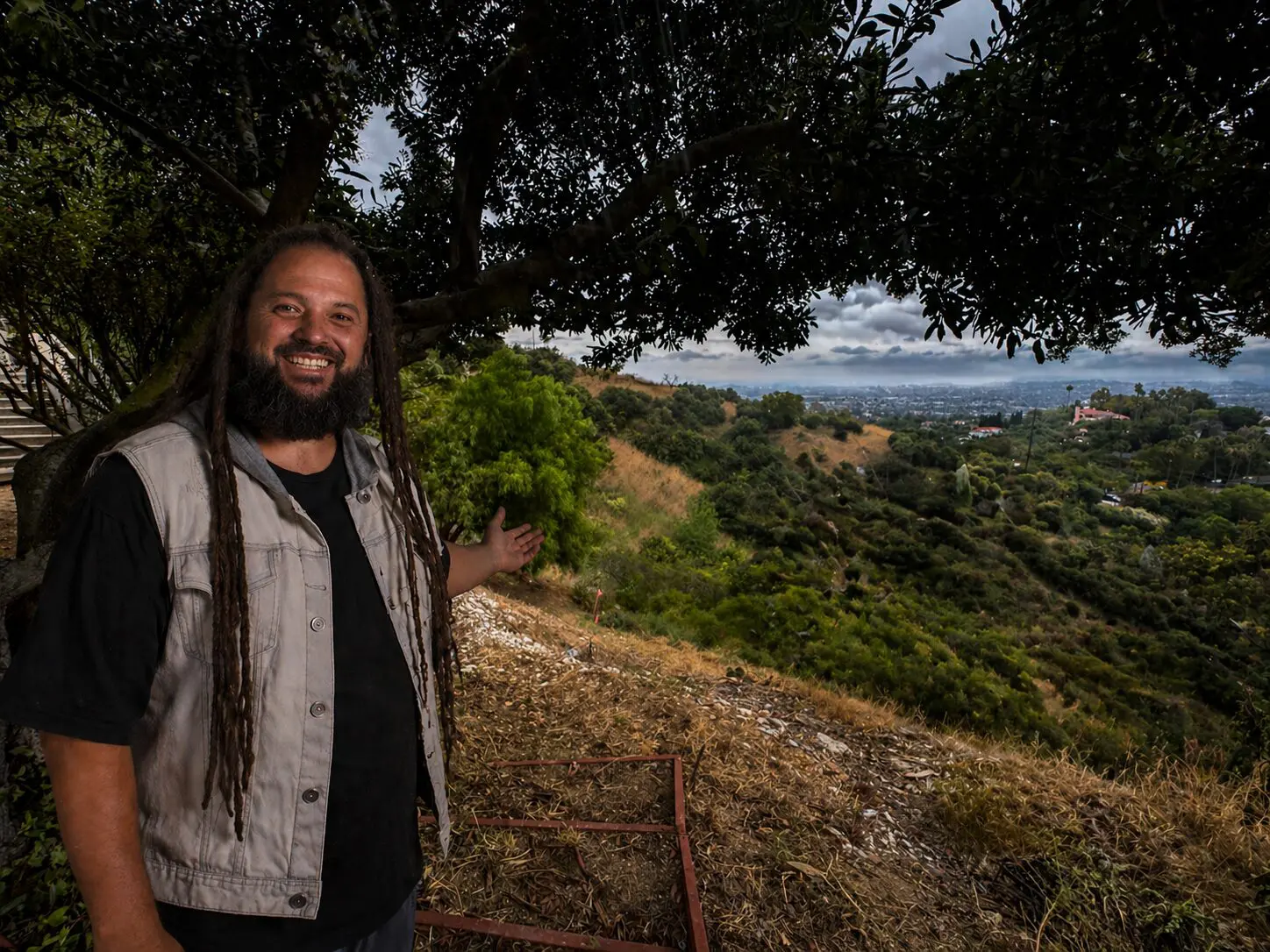 A La Habra Heights property owner pointing across his canyon, untouched hillside, distant city visible. © KAB / LSI