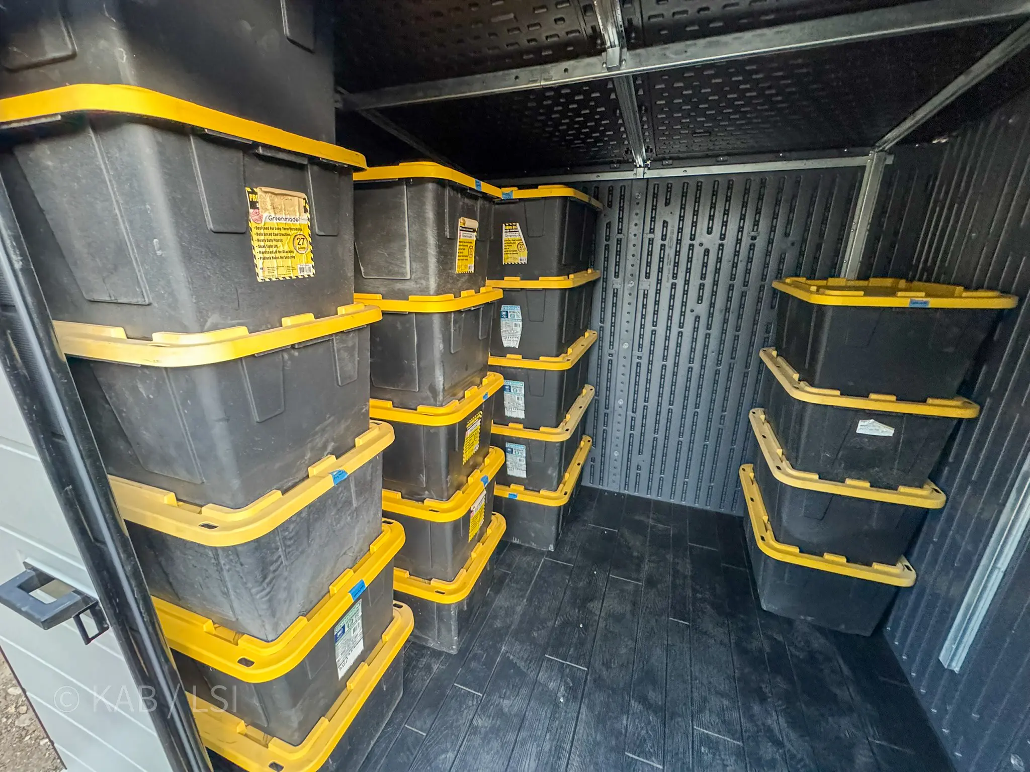 Interior of finished outbuilding with yellow-and-black storage totes stacked neatly on composite floor
