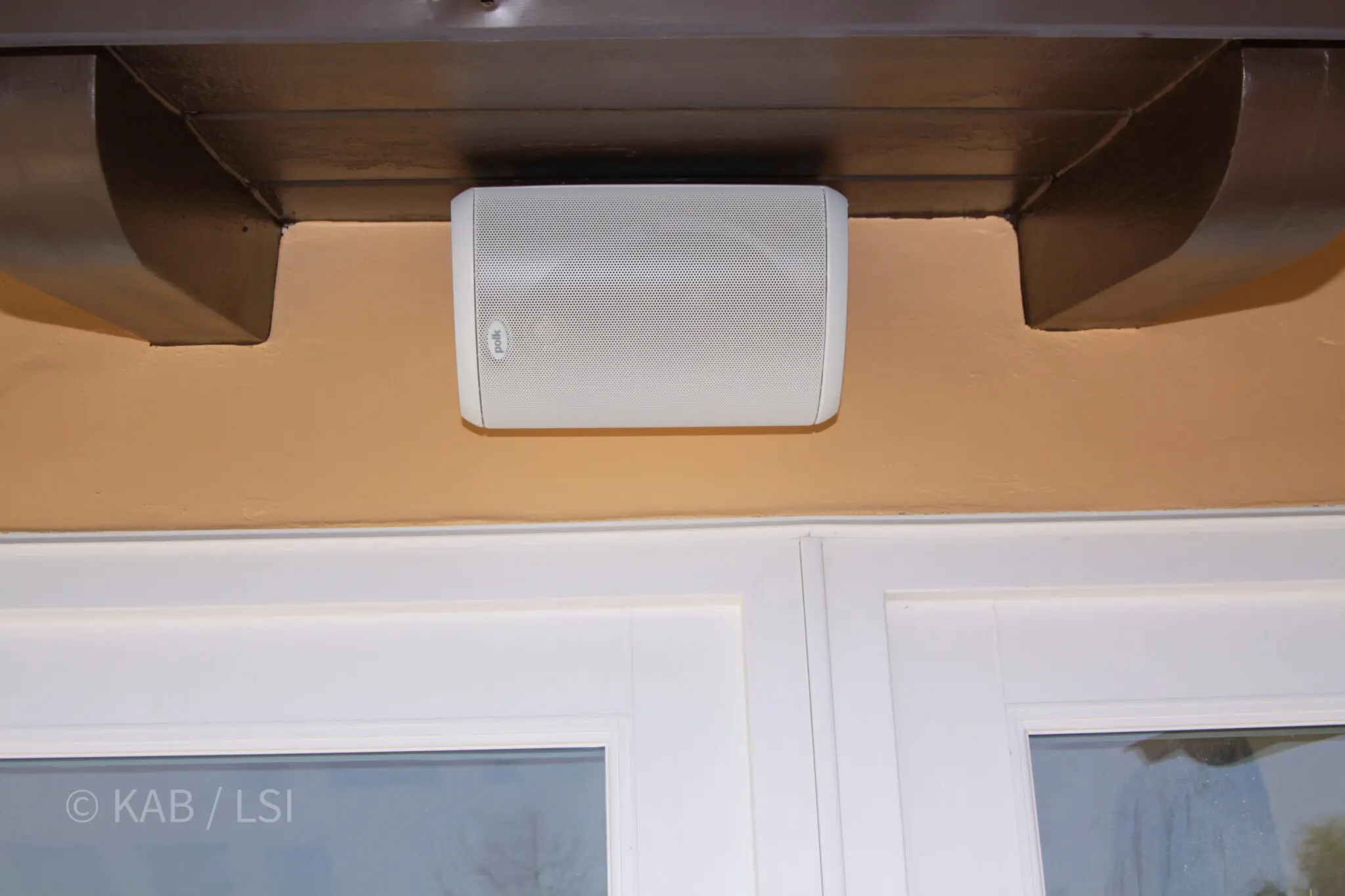 Outdoor speaker mounted flush under a timber eave with the wiring concealed inside the soffit