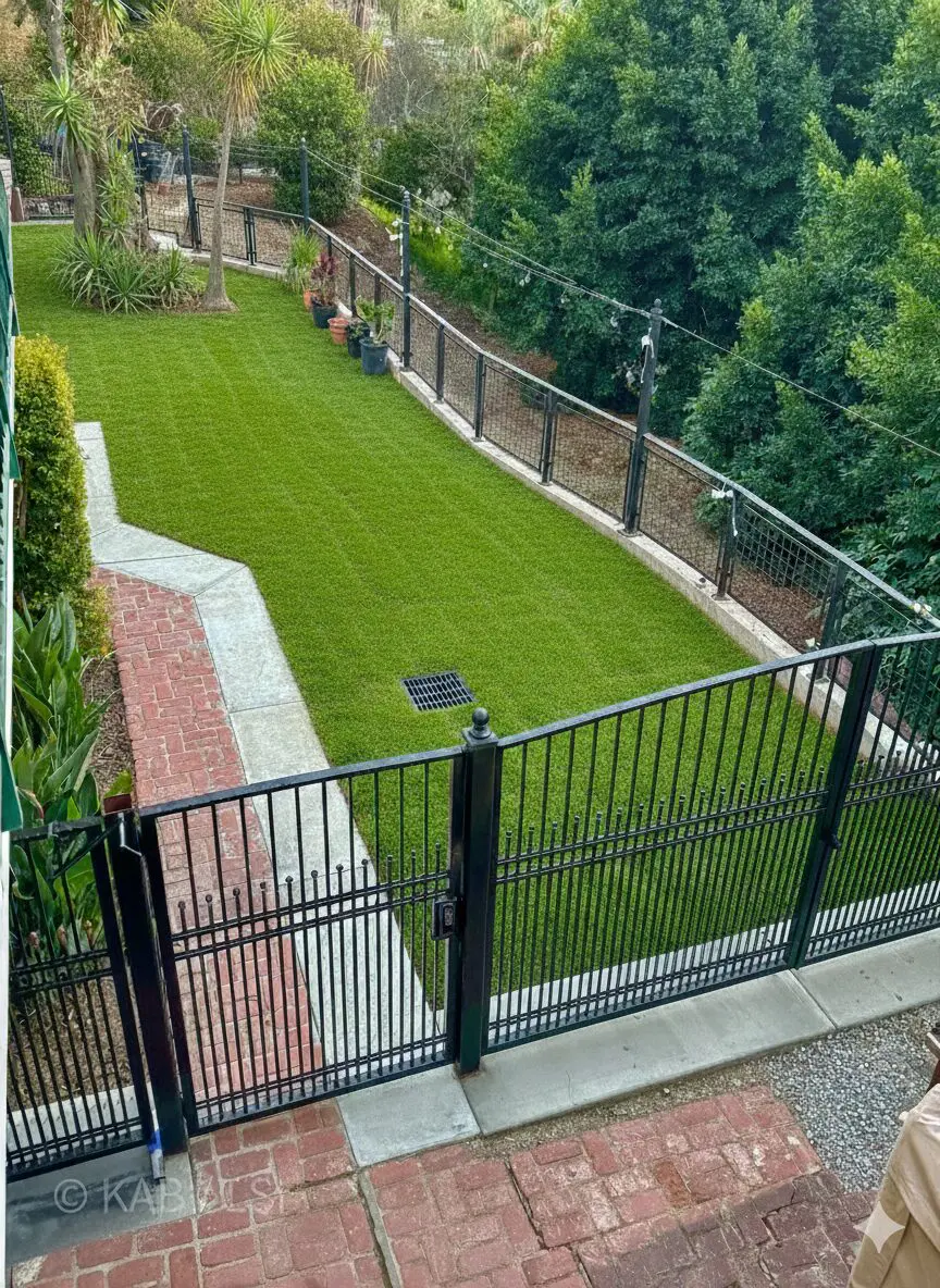 A finished hillside dog yard in La Habra Heights &mdash; 7&frac12;-foot wrought iron on level ground, a lower run atop a six-foot retaining wall.