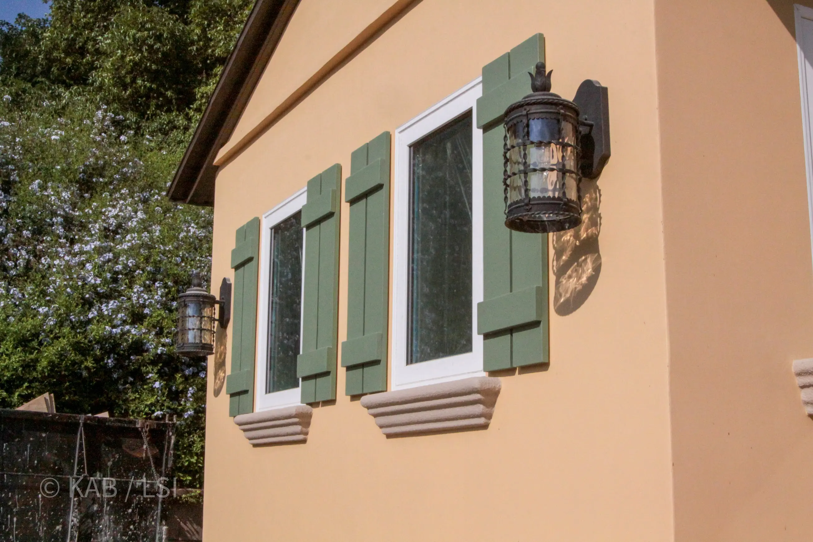 Sale-ready exterior of a La Habra Heights hillside home, with new stucco, paint, trim, green shutters, and iron lantern fixtures