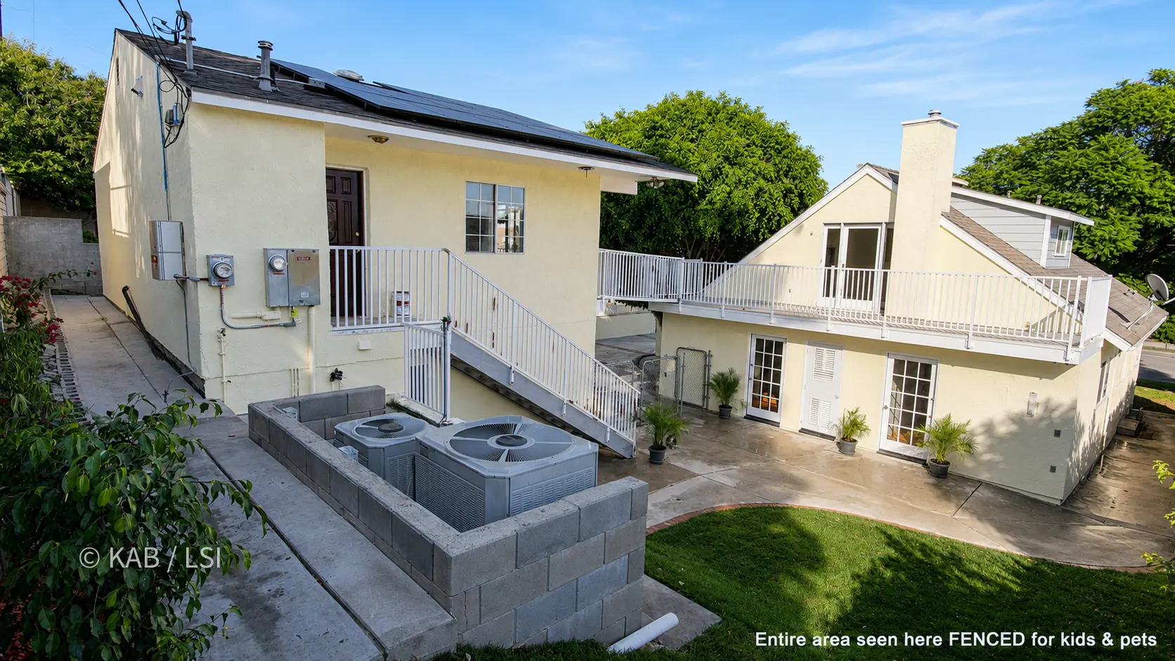 The completed 1988 La Mirada property seen from the rear corner — the three-car garage cut into the hillside, the eight-hundred-square-foot ADU above it, and the steel-and-aluminum bridge to the main house at right.