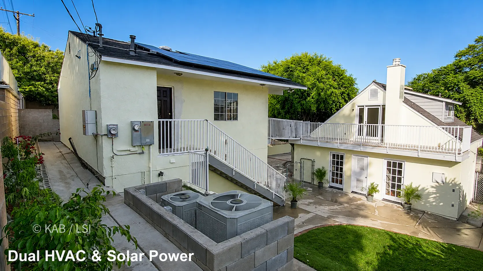 Rear of the property from the reclaimed hillside, HVAC condensers on a walled pad and solar on the ADU roof.