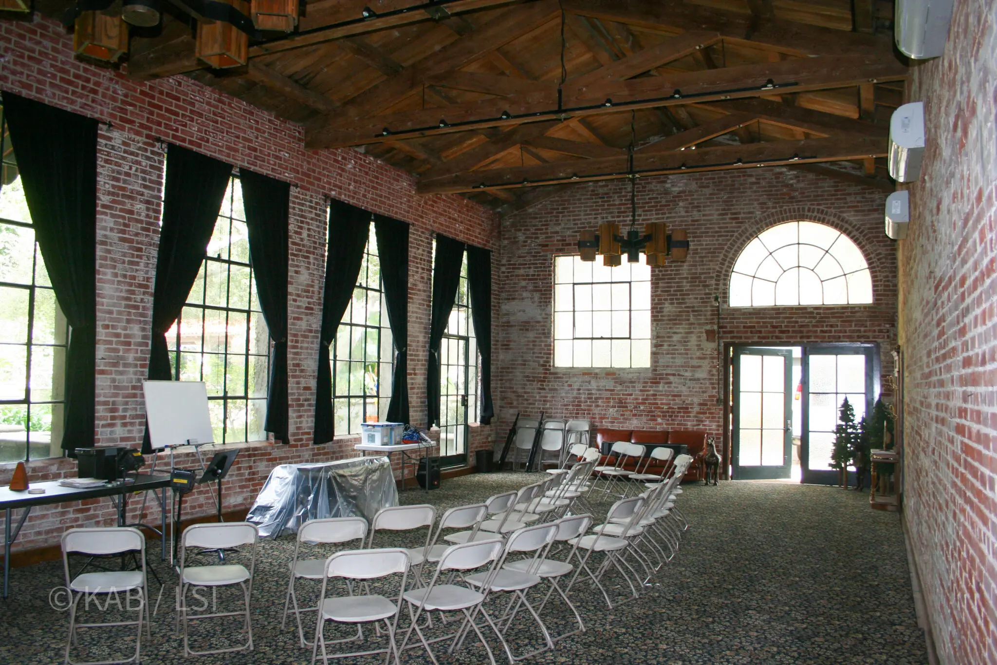 Interior of a 1920s brick carriage house with exposed timber trusses, tall steel windows and an arched fanlight