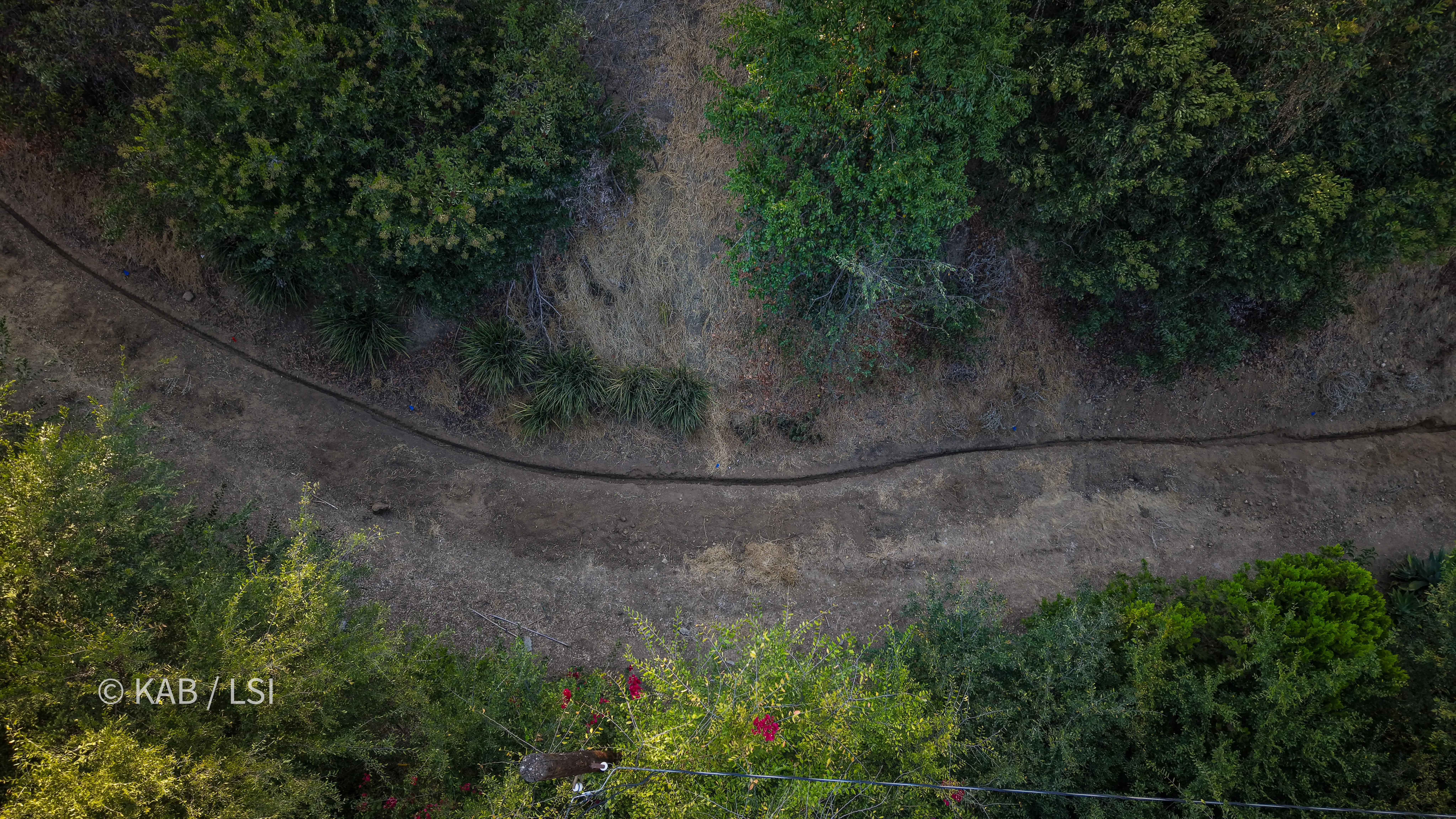 Aerial view of a four hundred and sixty foot water service trench cut as a single seam across a dry hillside on a hillside property in La Habra Heights