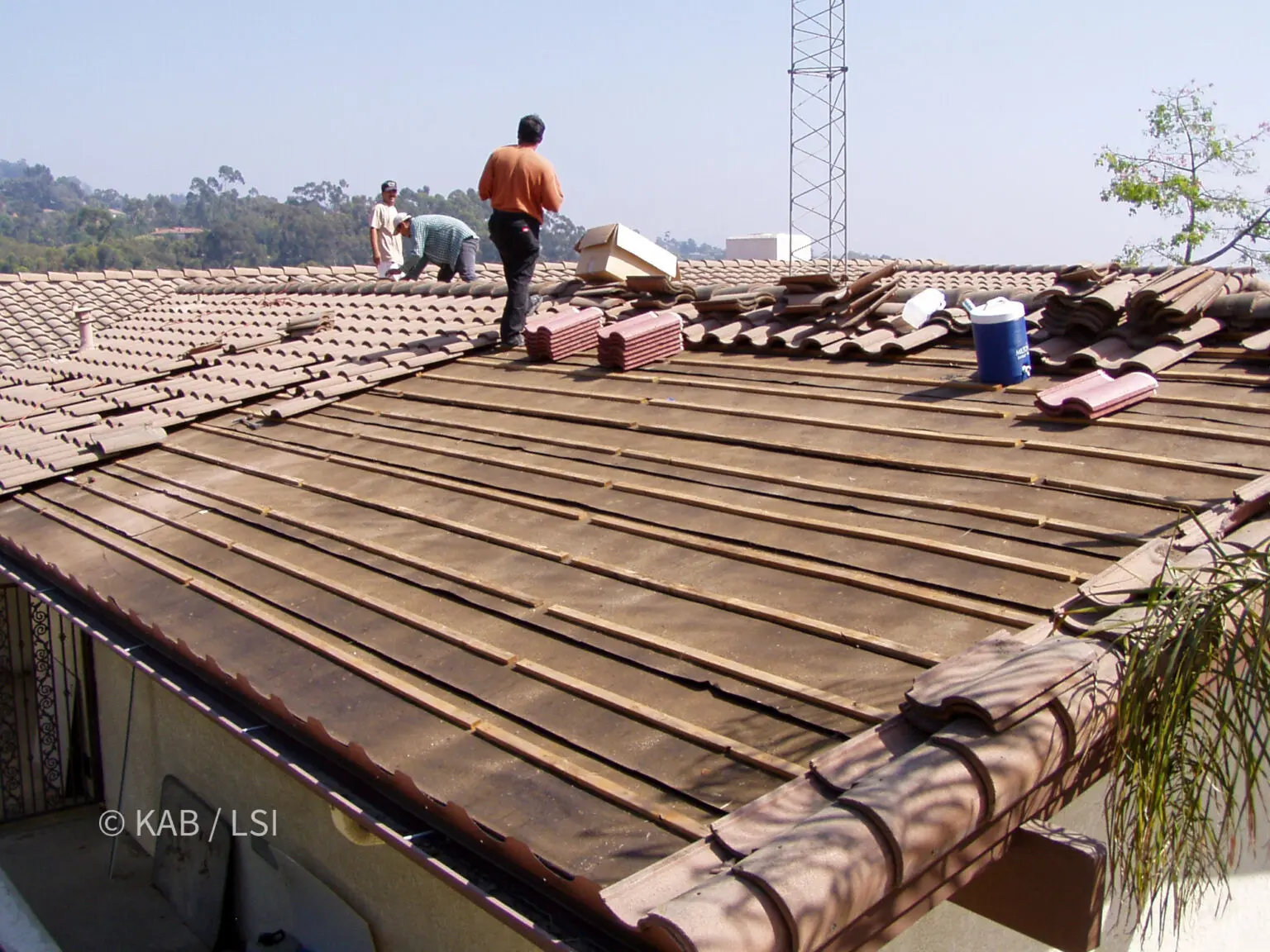 Concrete tile roof stripped back to battens and underlayment with tile stacked in courses for reinstallation