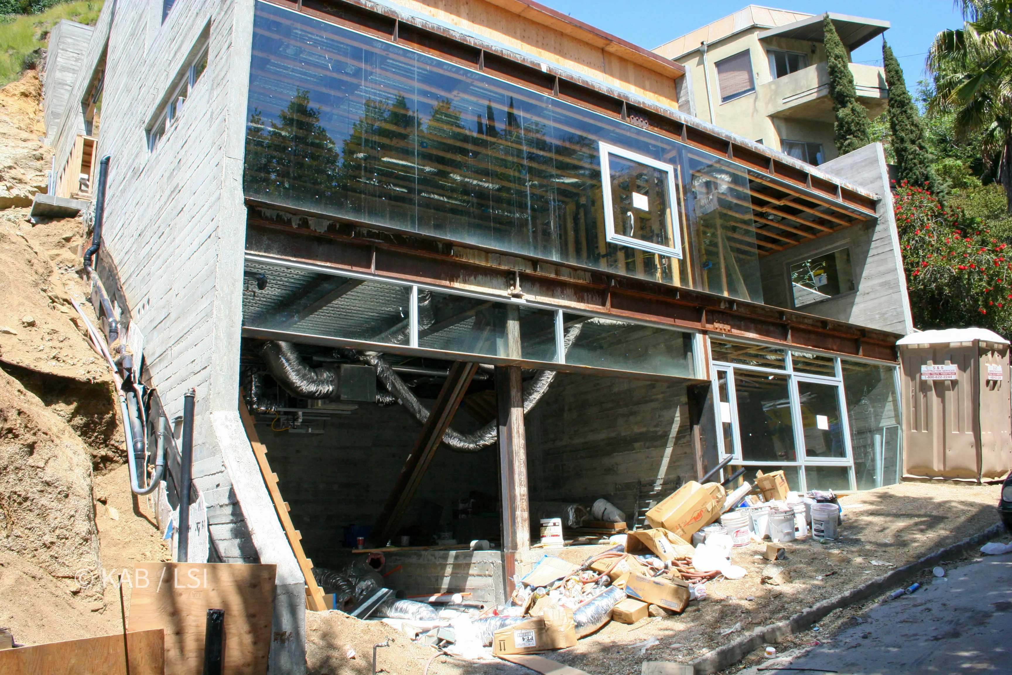 Concrete, steel and glass house under construction on a steep canyon lot with glazing installed