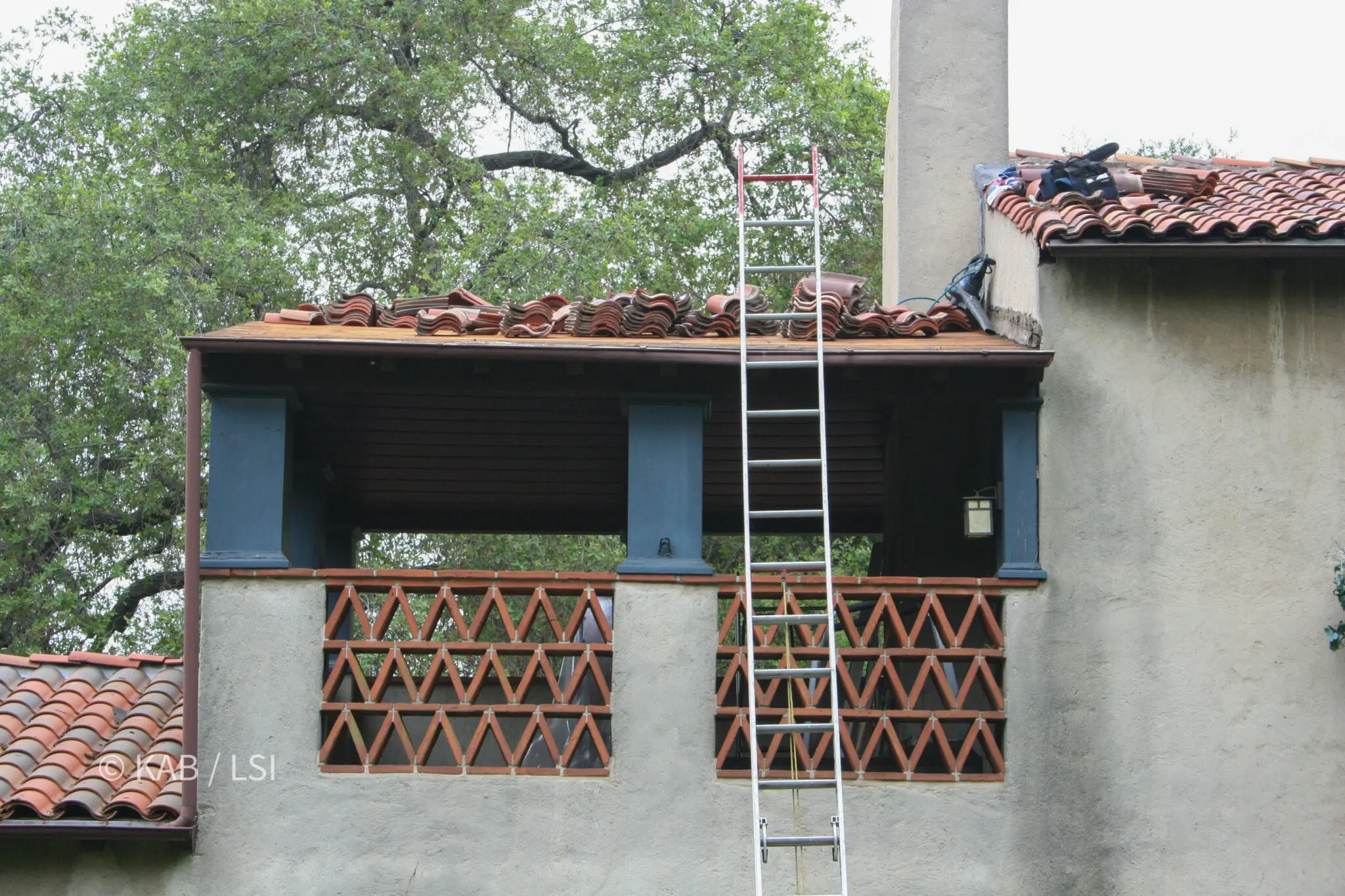Clay roof tiles removed and stacked on the roof of a 1920s house while the overhang below is rebuilt
