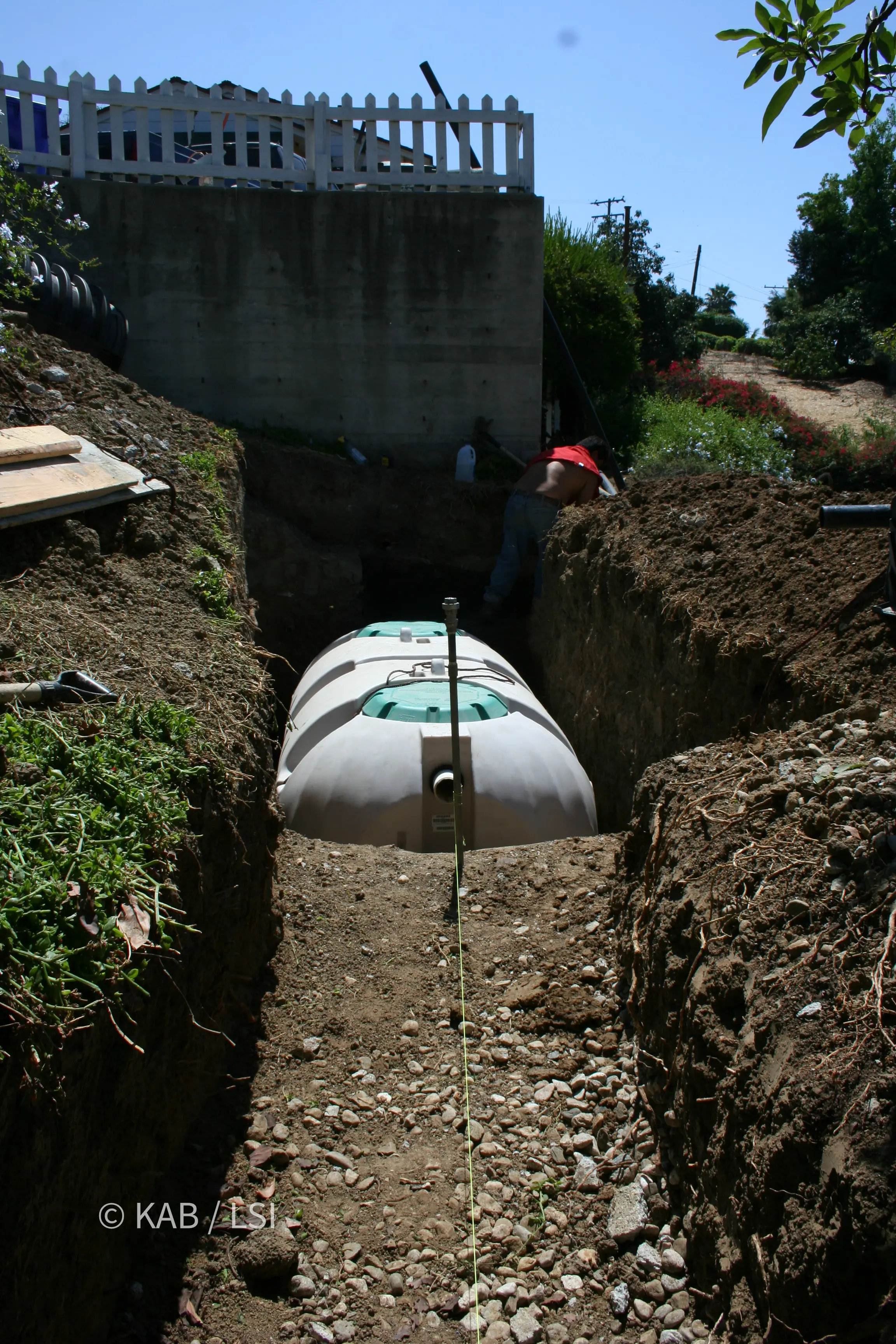 New white polyethylene septic tank lowered into a rectangular excavation