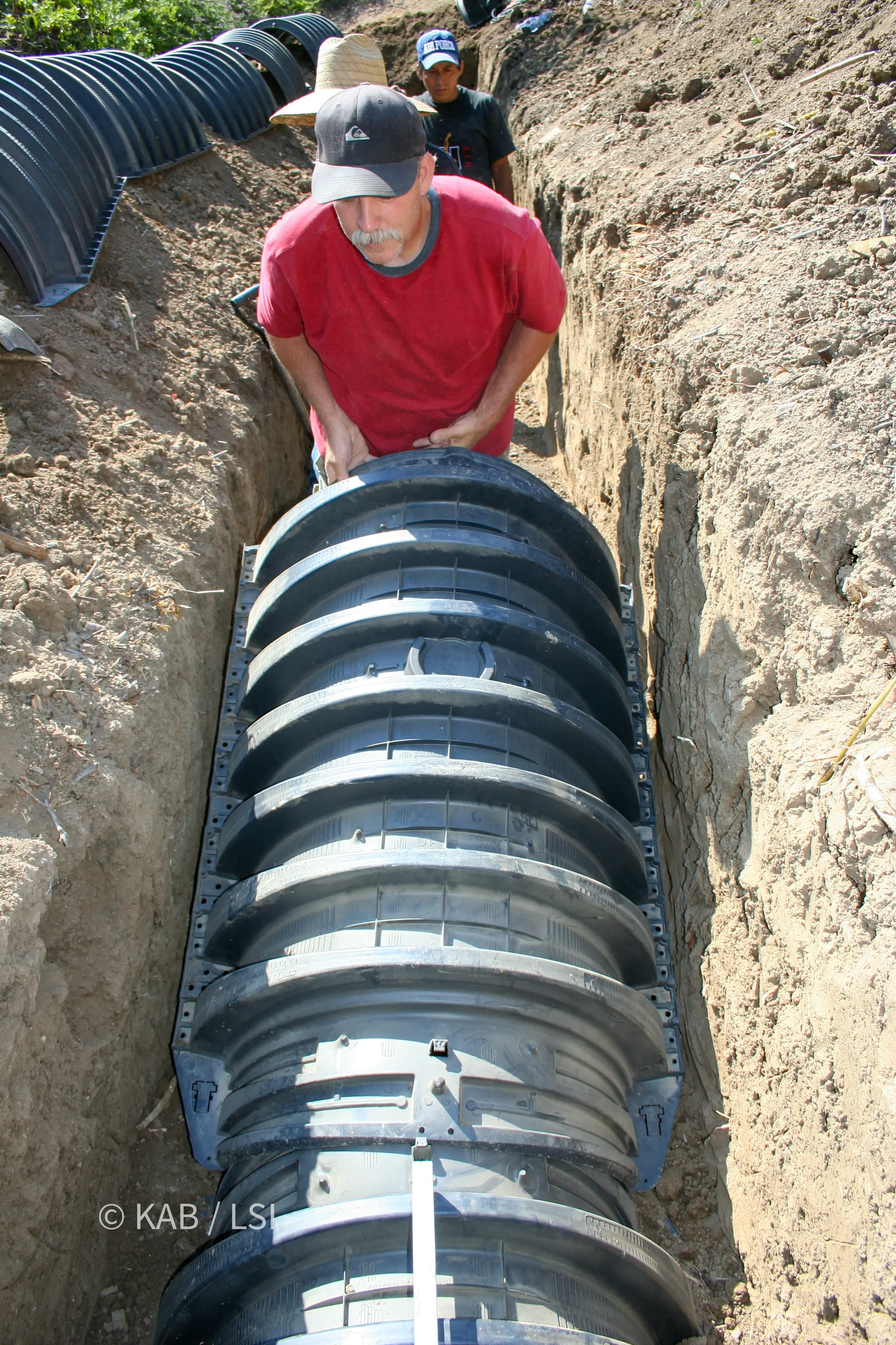 Interlocking arched chamber sections being installed in a modern hillside leach field