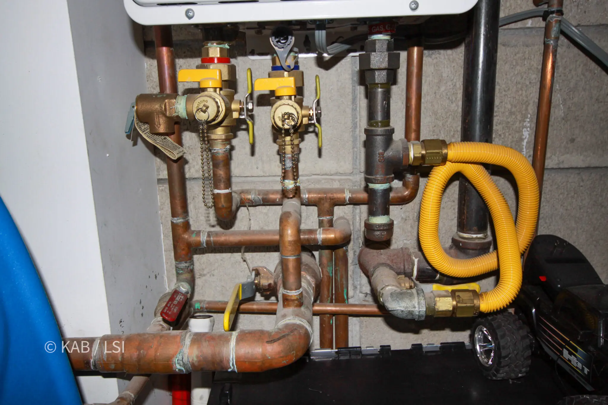 Isolation valves and flush ports below a tankless water heater with organized copper plumbing