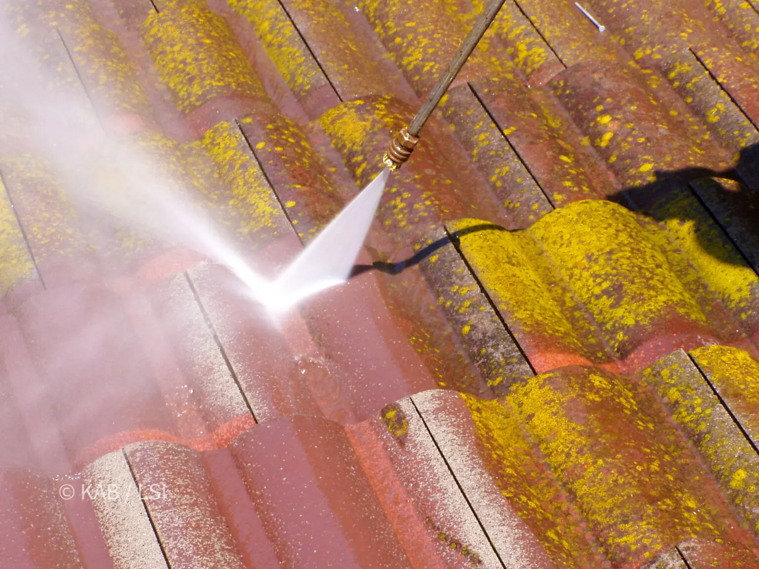 Pressure washing decades of algae and particulate fallout from concrete roof tile