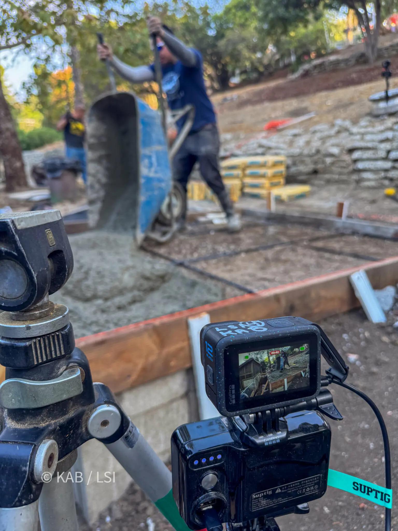 Concrete finisher and helper mixing concrete on site for a hillside shed pad in La Habra Heights