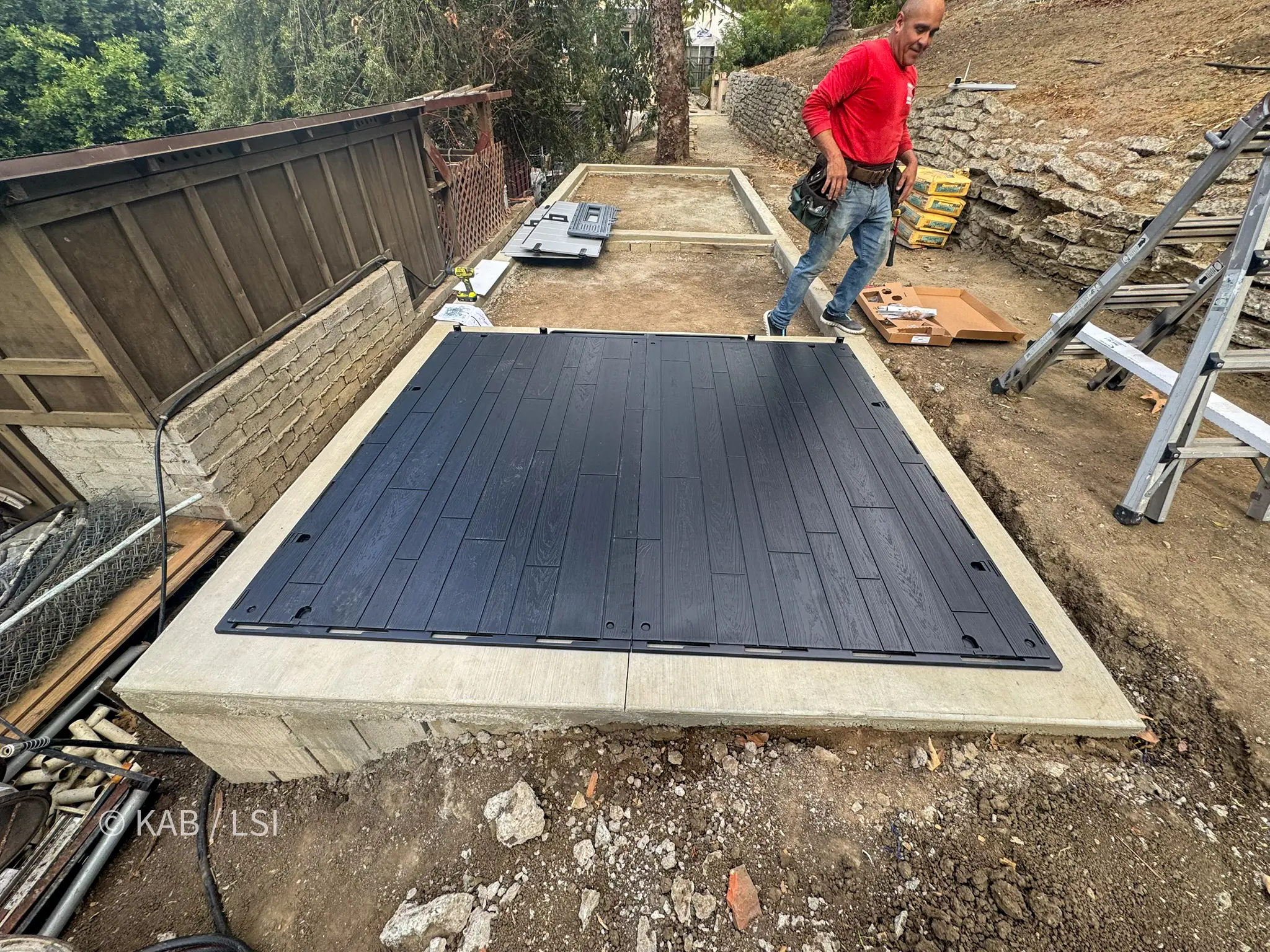 Handyman assembling the floor panel of a Lifetime storage shed on a new concrete pad