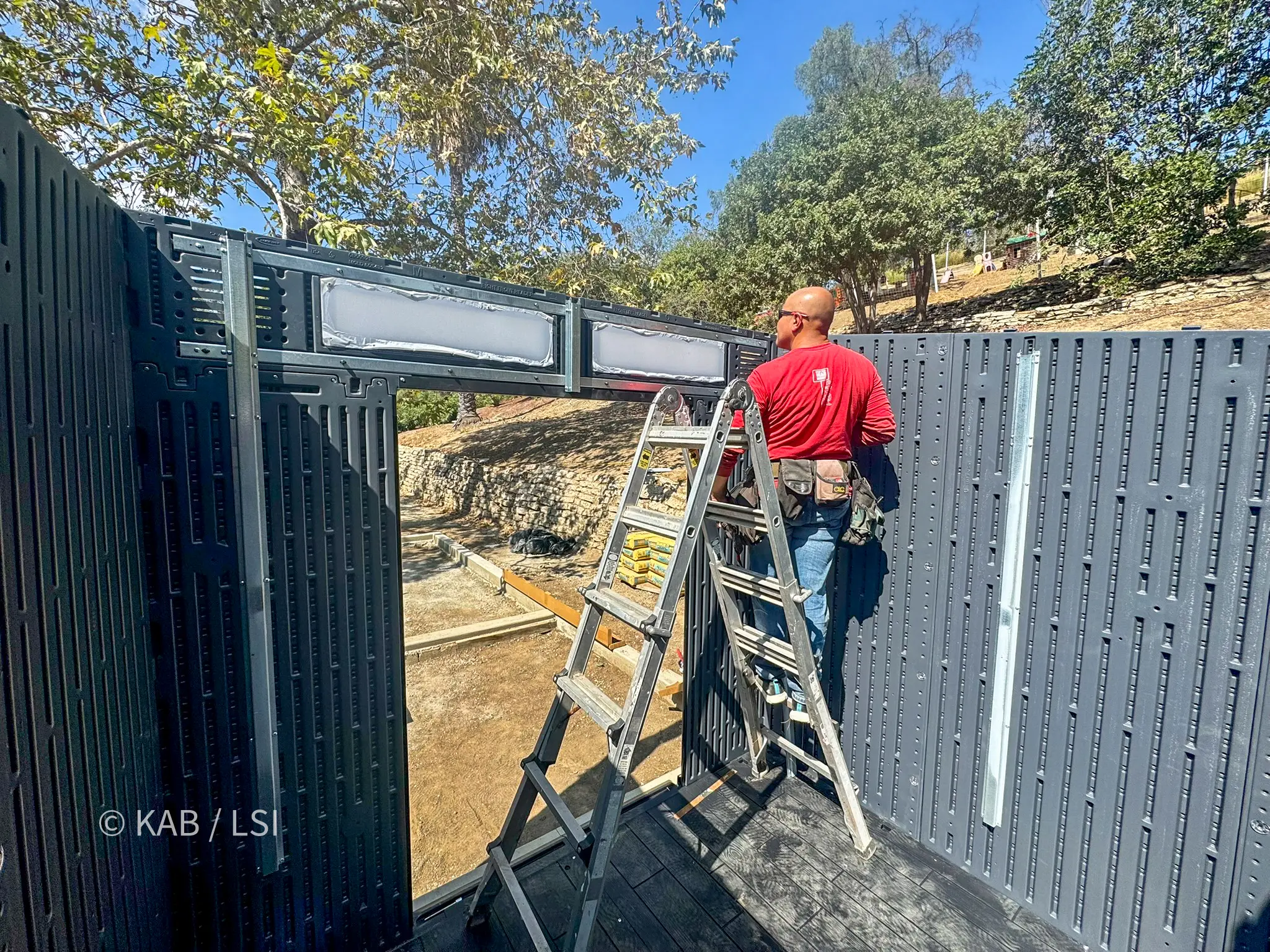 Storage shed walls taking shape during a Lifetime shed installation on a hillside property