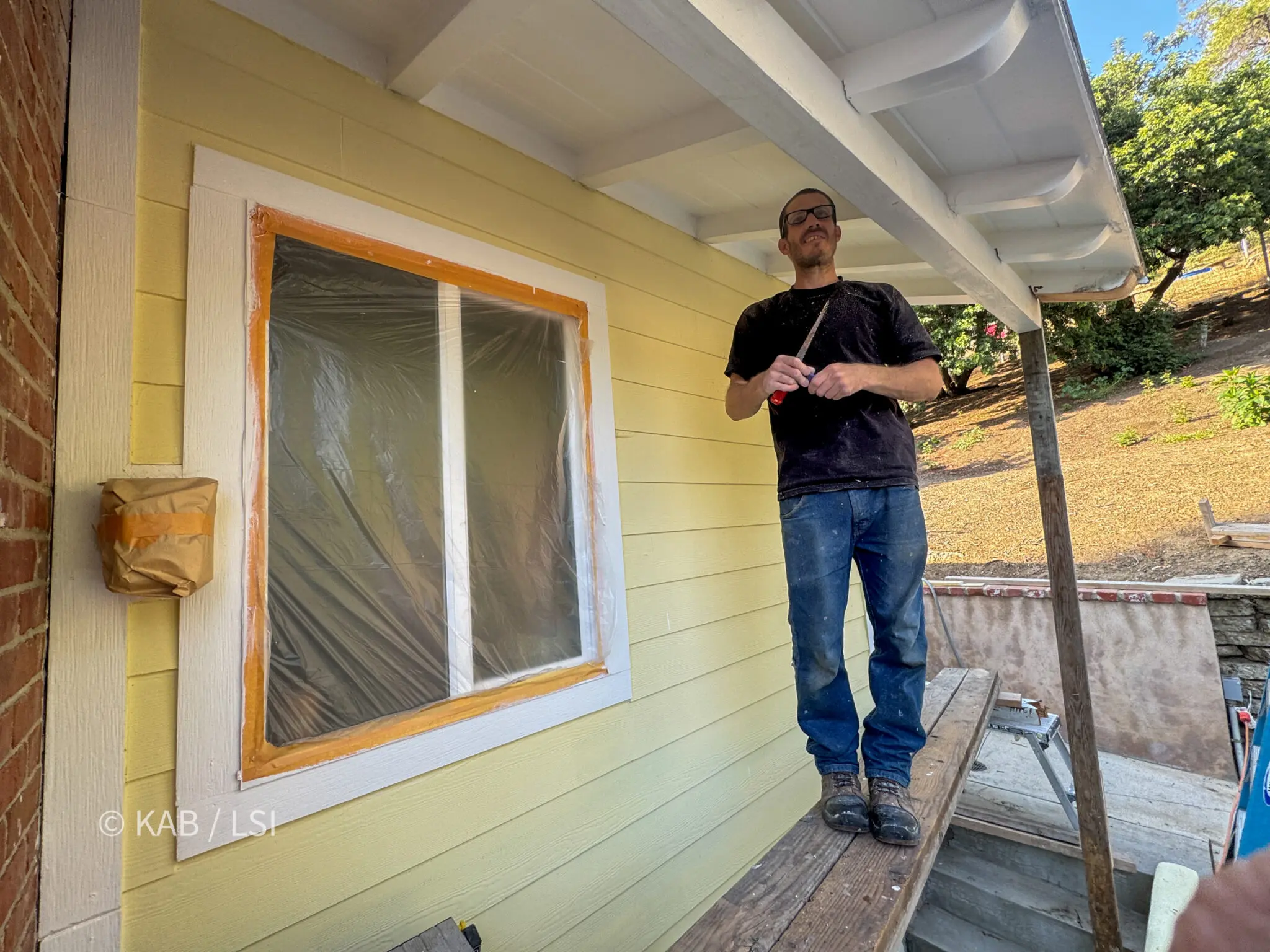 Handyman repairing termite-damaged roof overhangs on a La Habra Heights hillside home