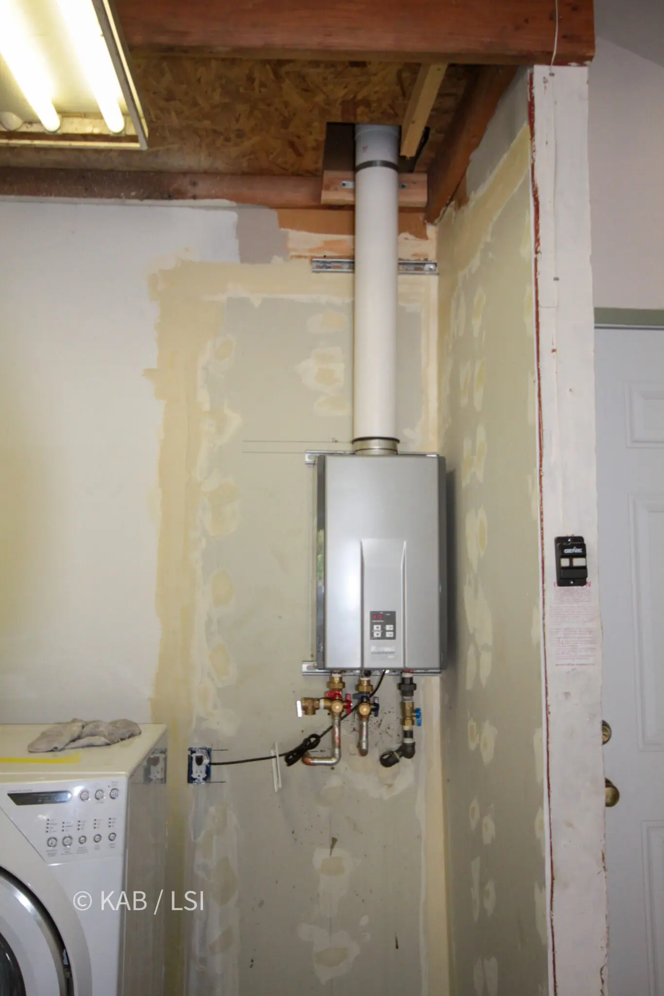 Wall-mounted tankless water heater and its gas and water connections in the space the closet used to occupy