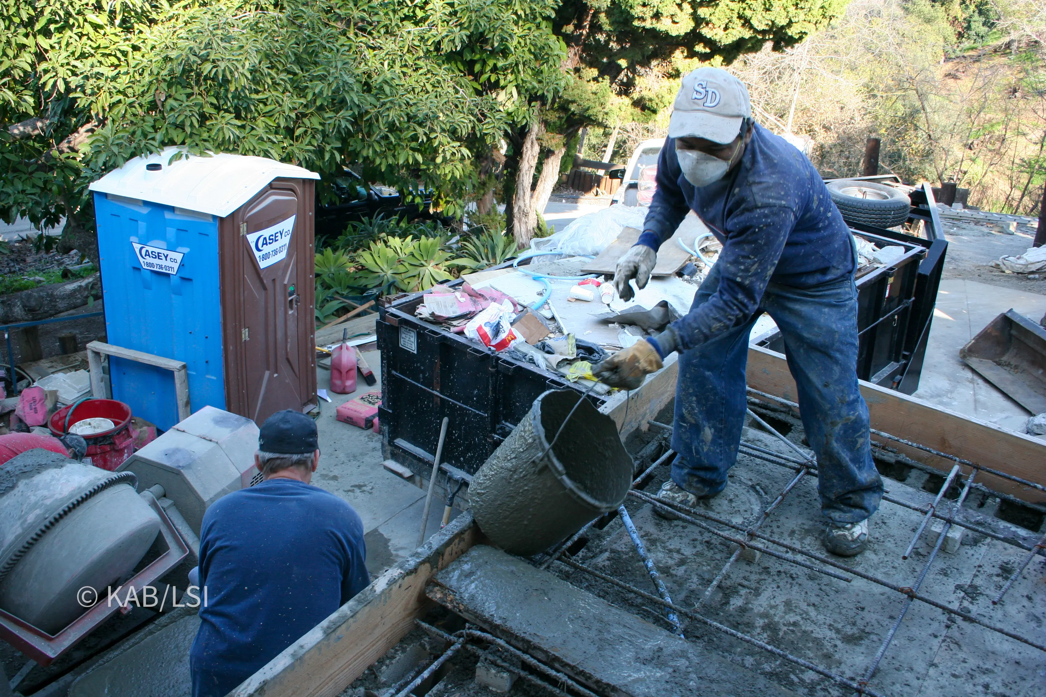 Workers pouring the reinforced concrete roof slab over a concrete masonry safe room