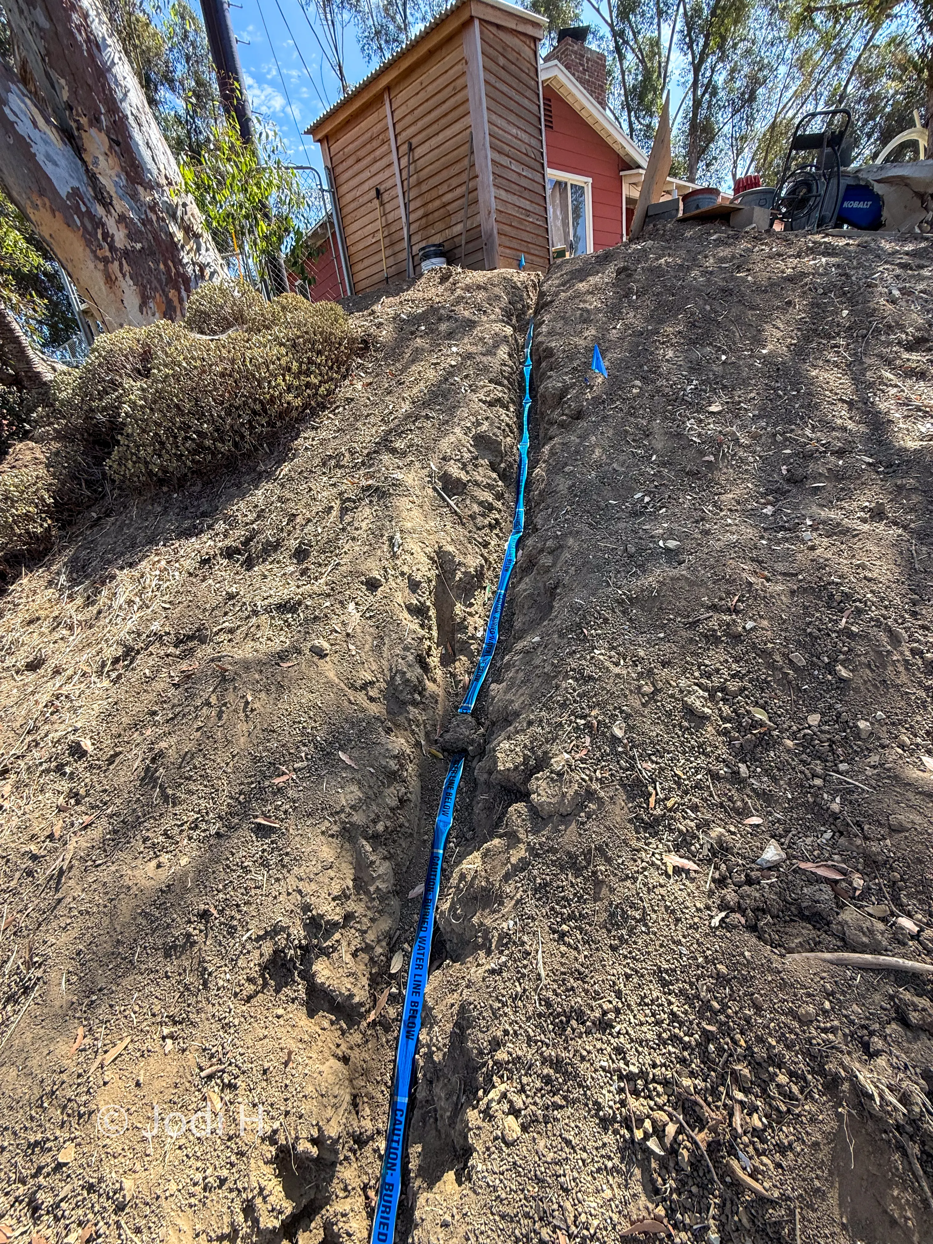 Open water service trench climbing a steep hillside slope in La Habra Heights