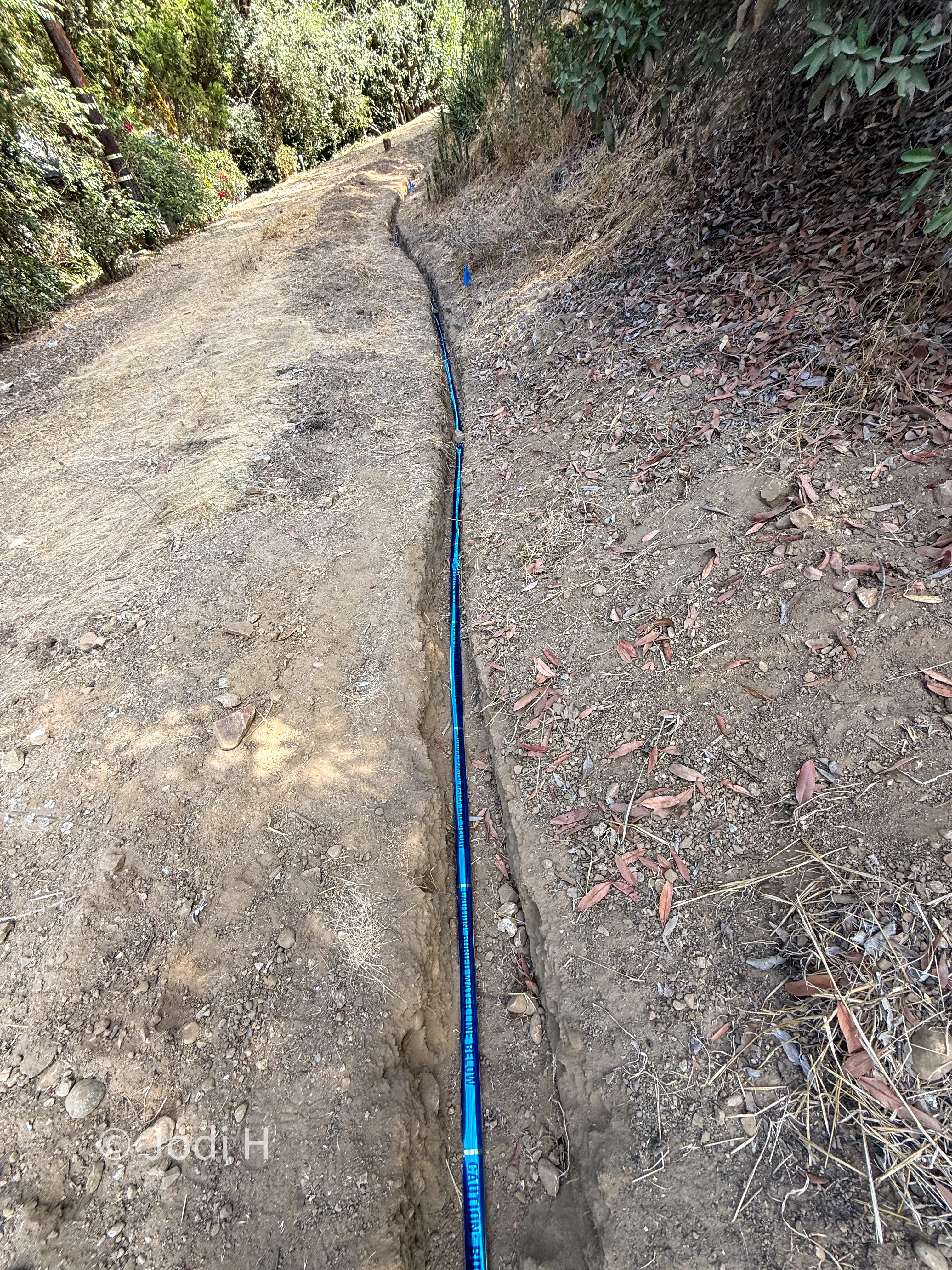 Backfilled and healed water service trench across a hillside slope