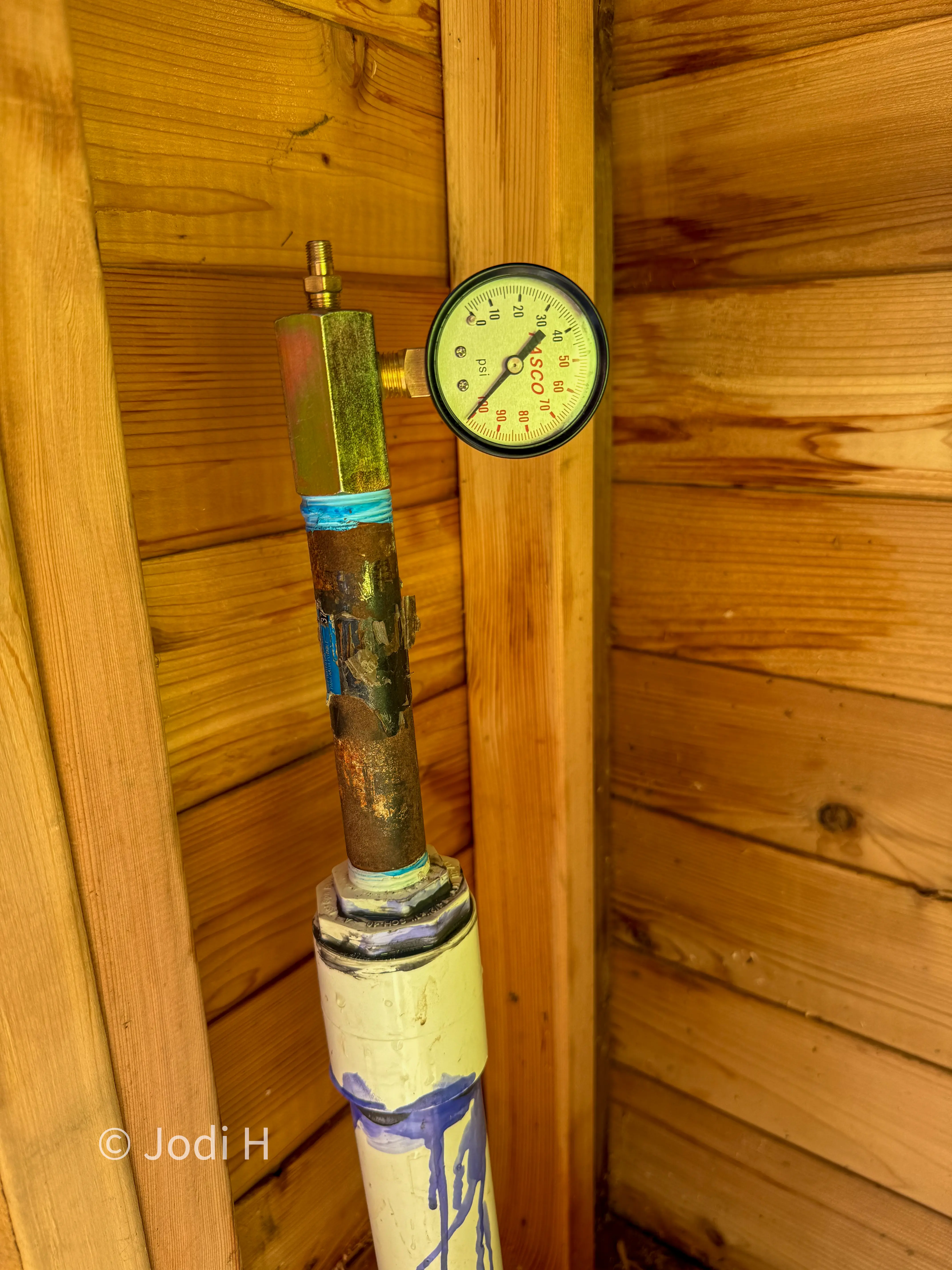 Temporary test gauge on a capped water service riser during an air pressure test before backfilling