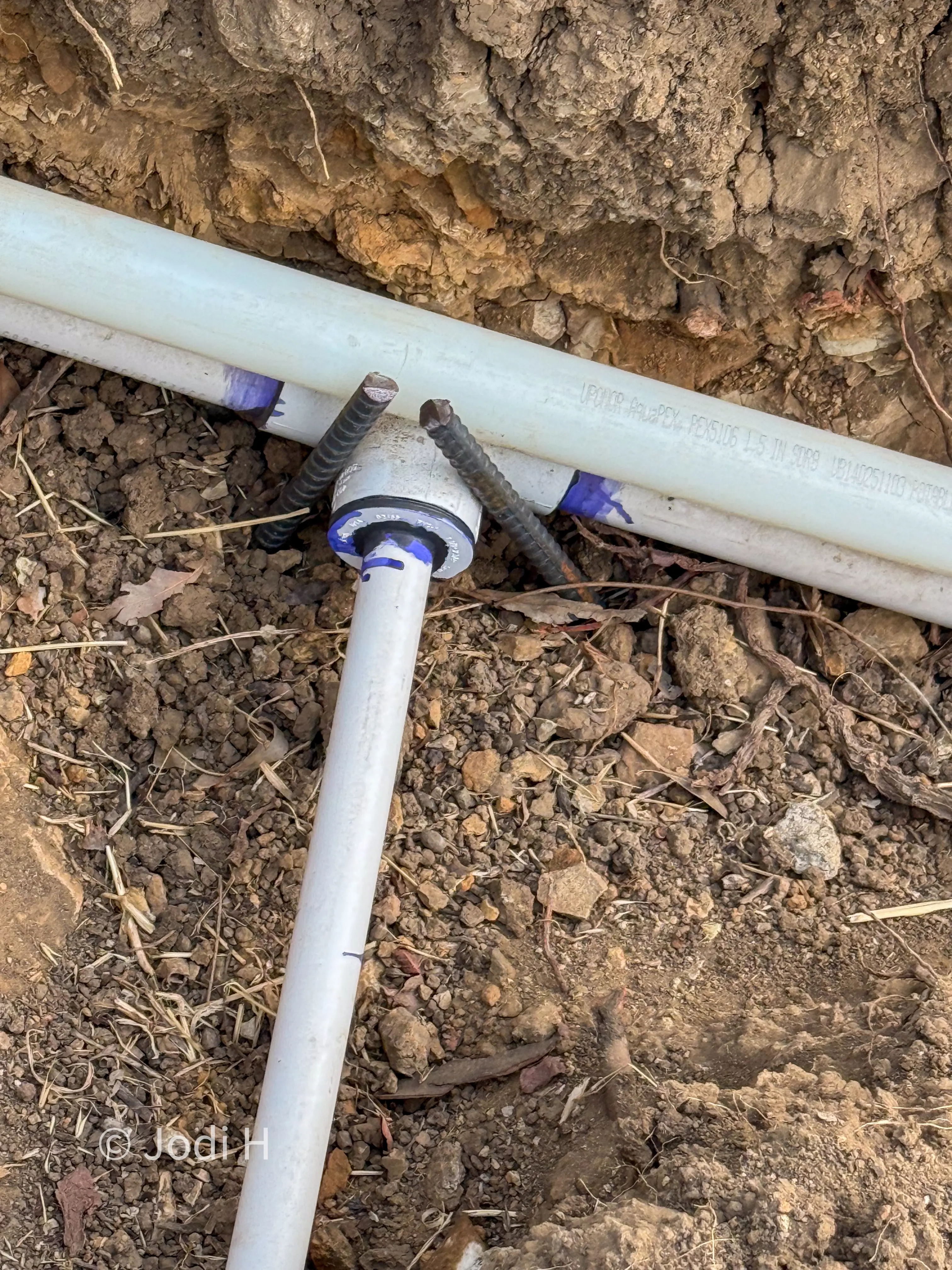 Close-up of an integral bell connection on inch-and-a-half PVC water main pipe in a trench