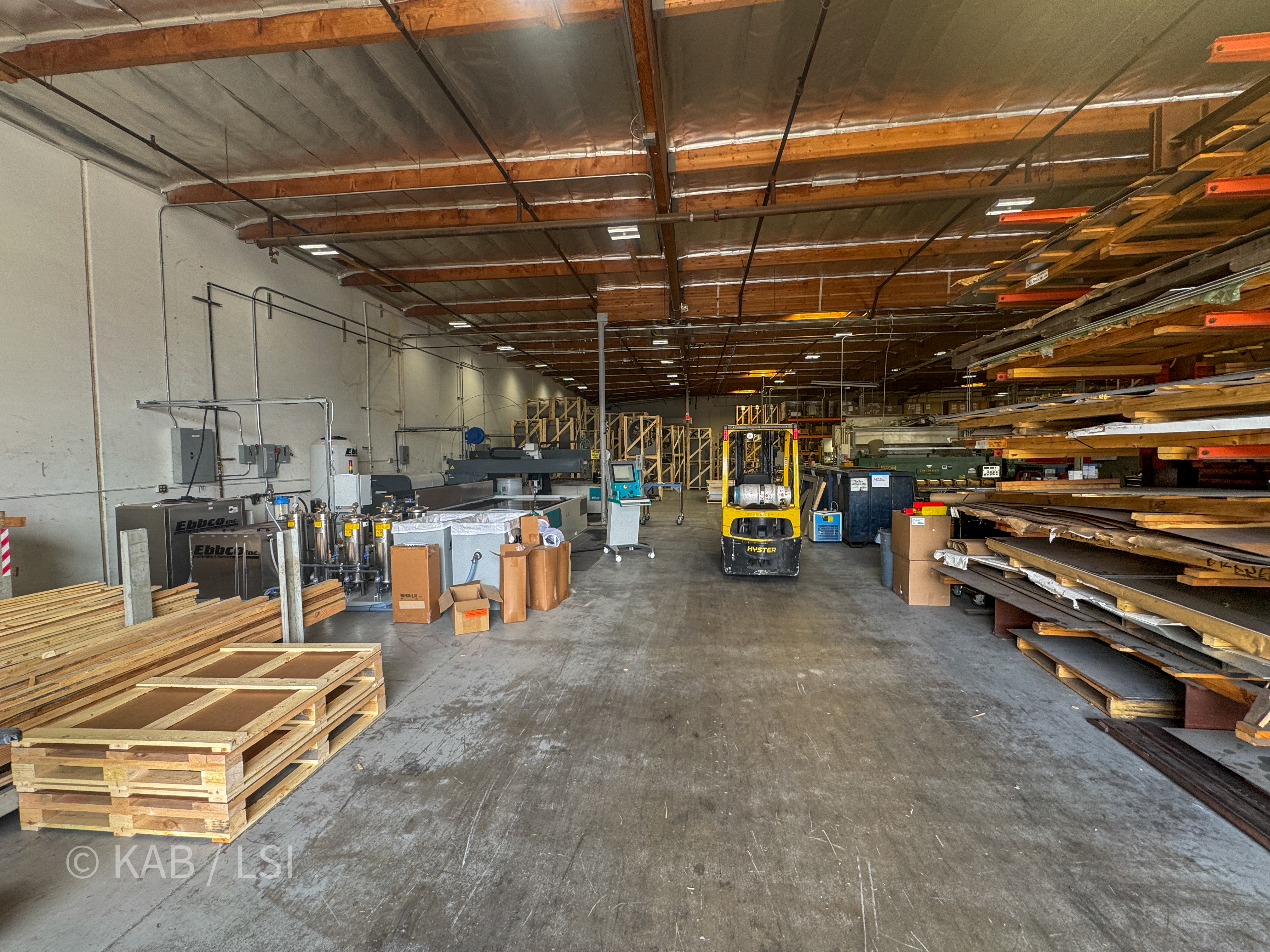 Interior view of the ToroAire fabrication floor showing a water-jet CNC cutting table, Ebbco closed-loop water filtration units, sheet stock racking, and a Hyster propane forklift.