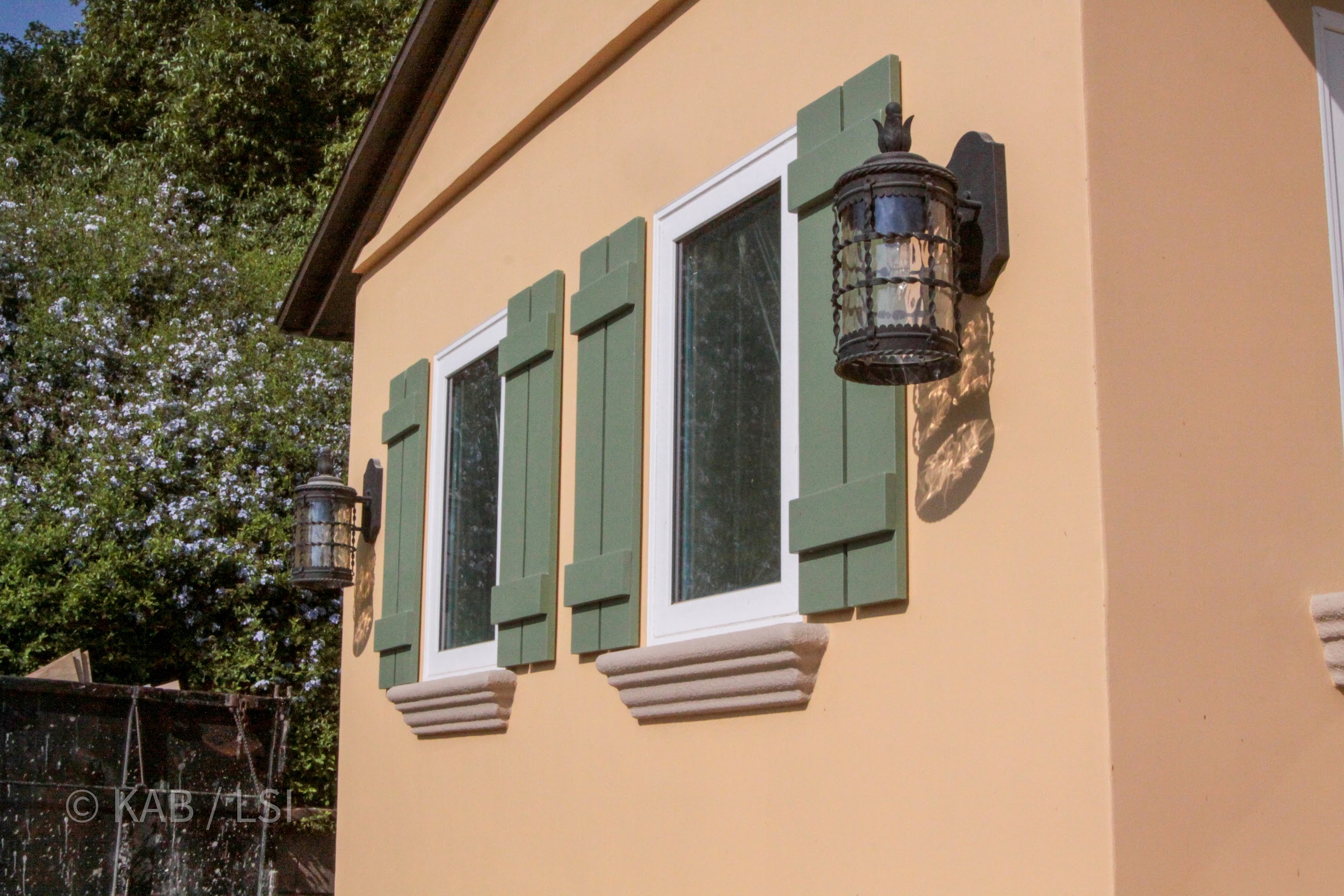 Sale-ready exterior of a La Habra Heights hillside home, with new stucco, paint, trim, green shutters, and iron lantern fixtures