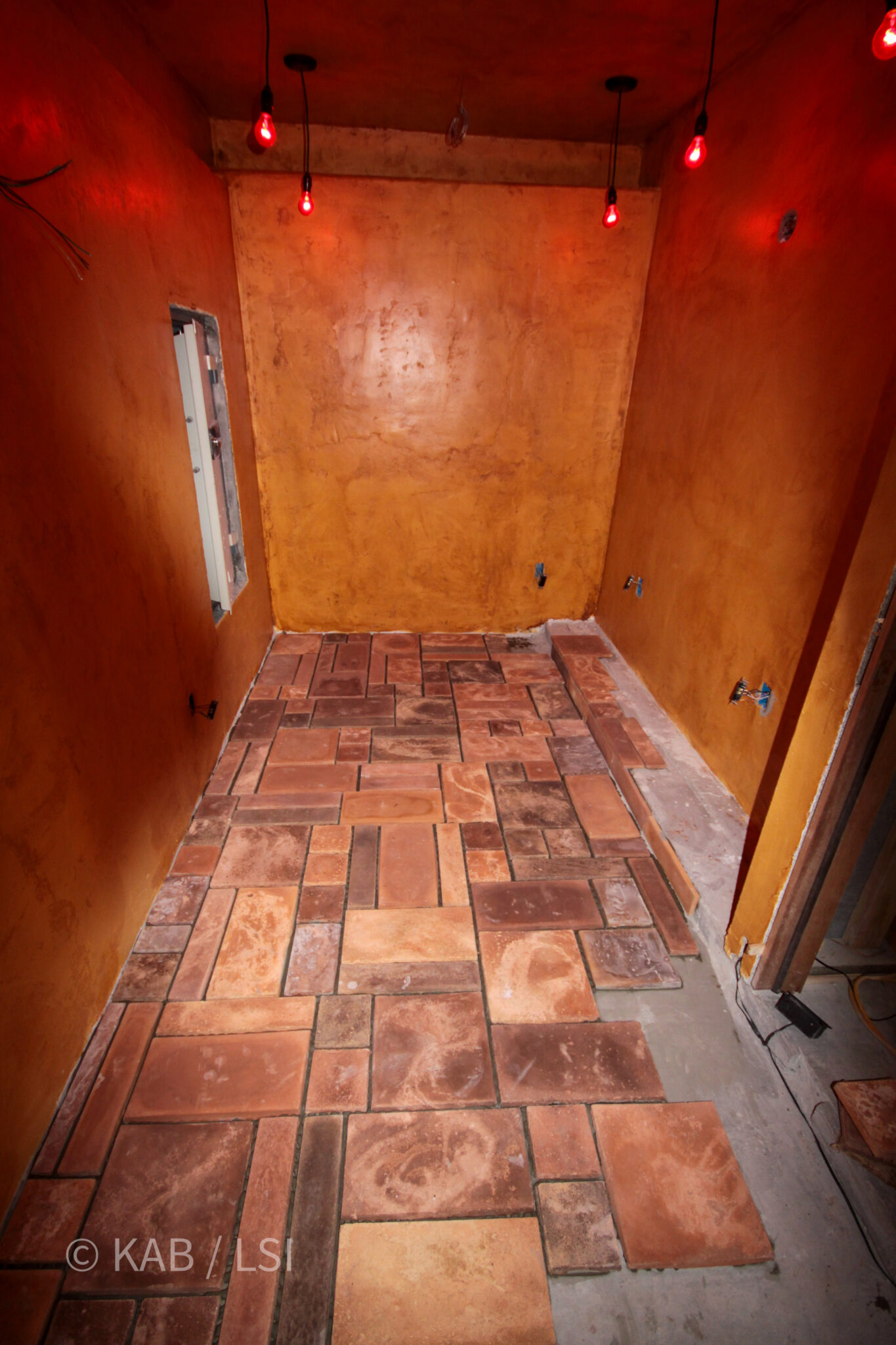 Handmade Saltillo tile floor installation — cast concrete safe room with Italian stucco walls and red work lighting, La Habra Heights © KAB/LSI