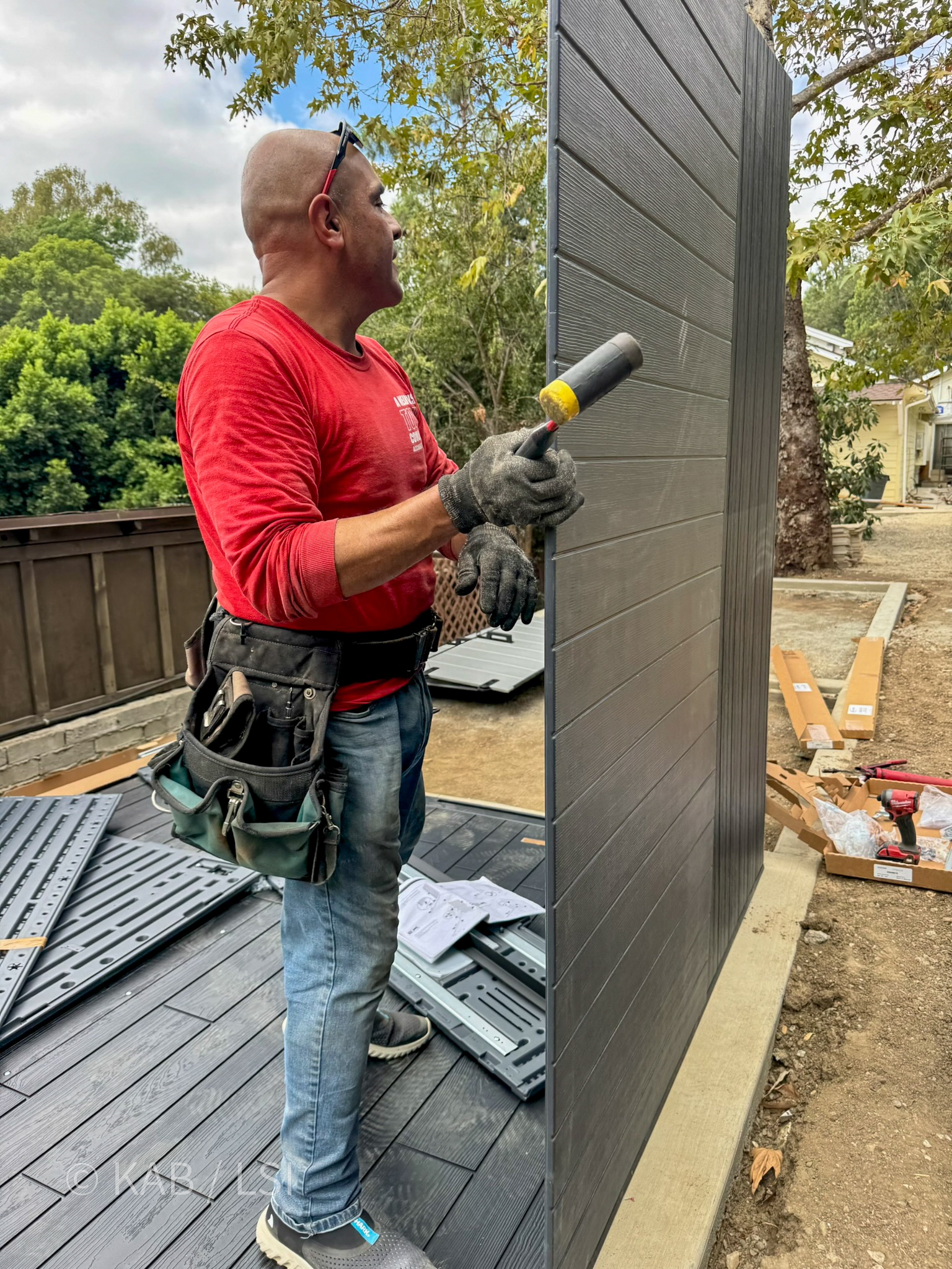 Professional assembly technician with tool belt assembling Costco shed on new concrete pad La Habra Heights hillside property