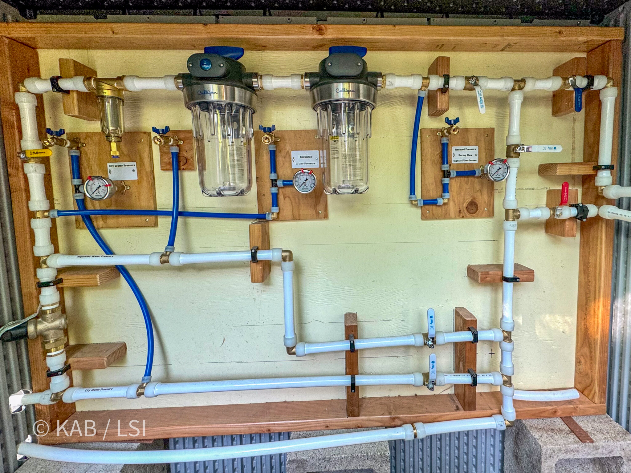 Complete whole house water processing filtering and softening system with Culligan filter housings pressure gauges and labeled PEX manifold board