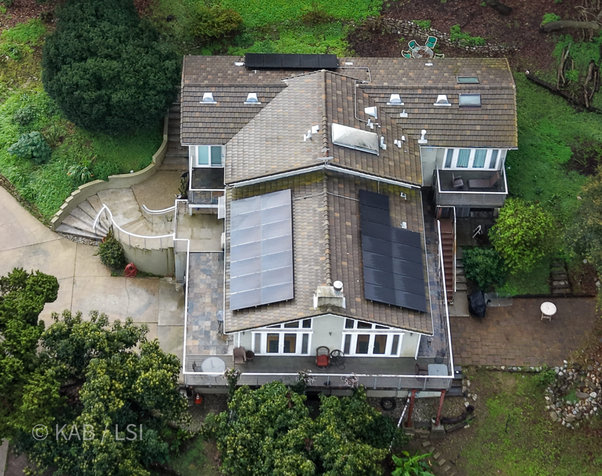 Aerial view of La Habra Heights hillside estate with solar panels curved staircase and mature tree canopy